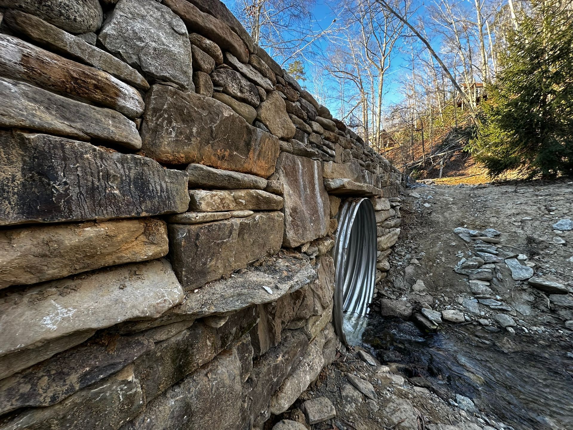 A stone wall with a metal pipe coming out of it.
