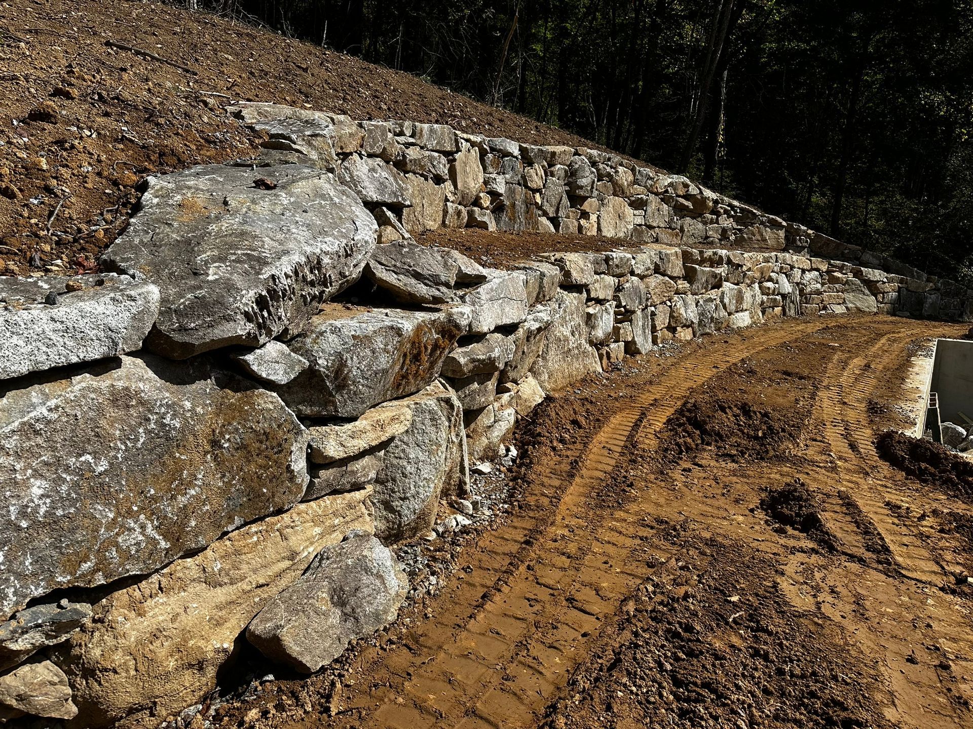 A large rock wall is sitting on top of a dirt hill.