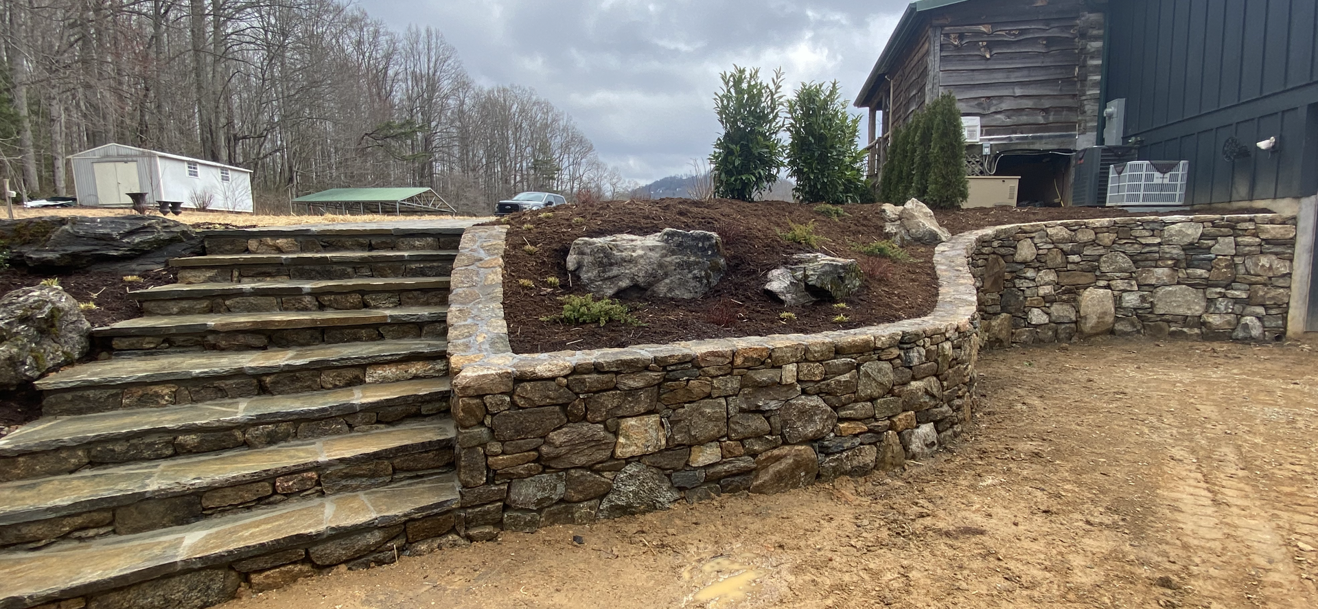 A stone wall with stairs leading up to a house.