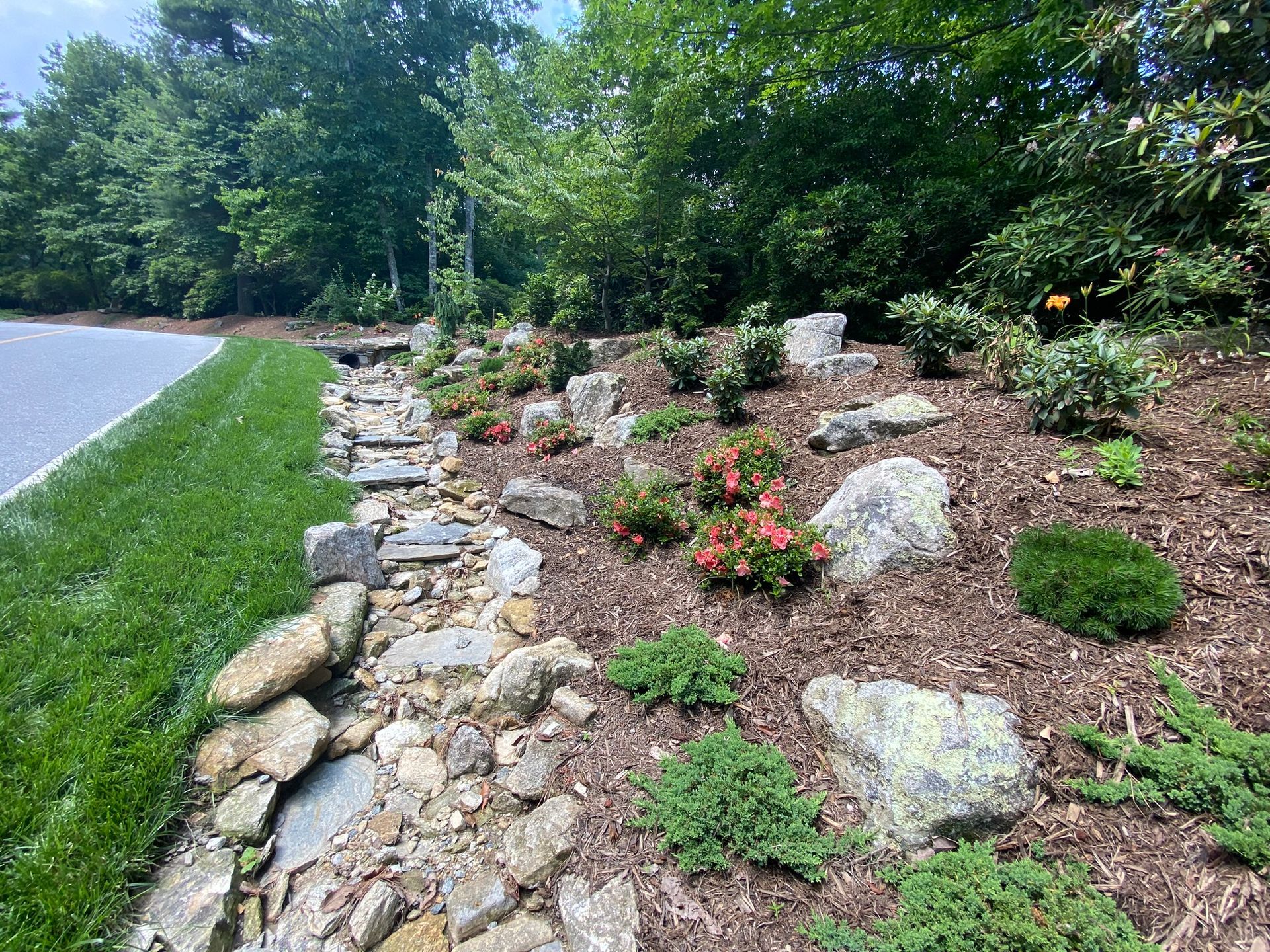 A lush green lawn surrounded by rocks and trees.