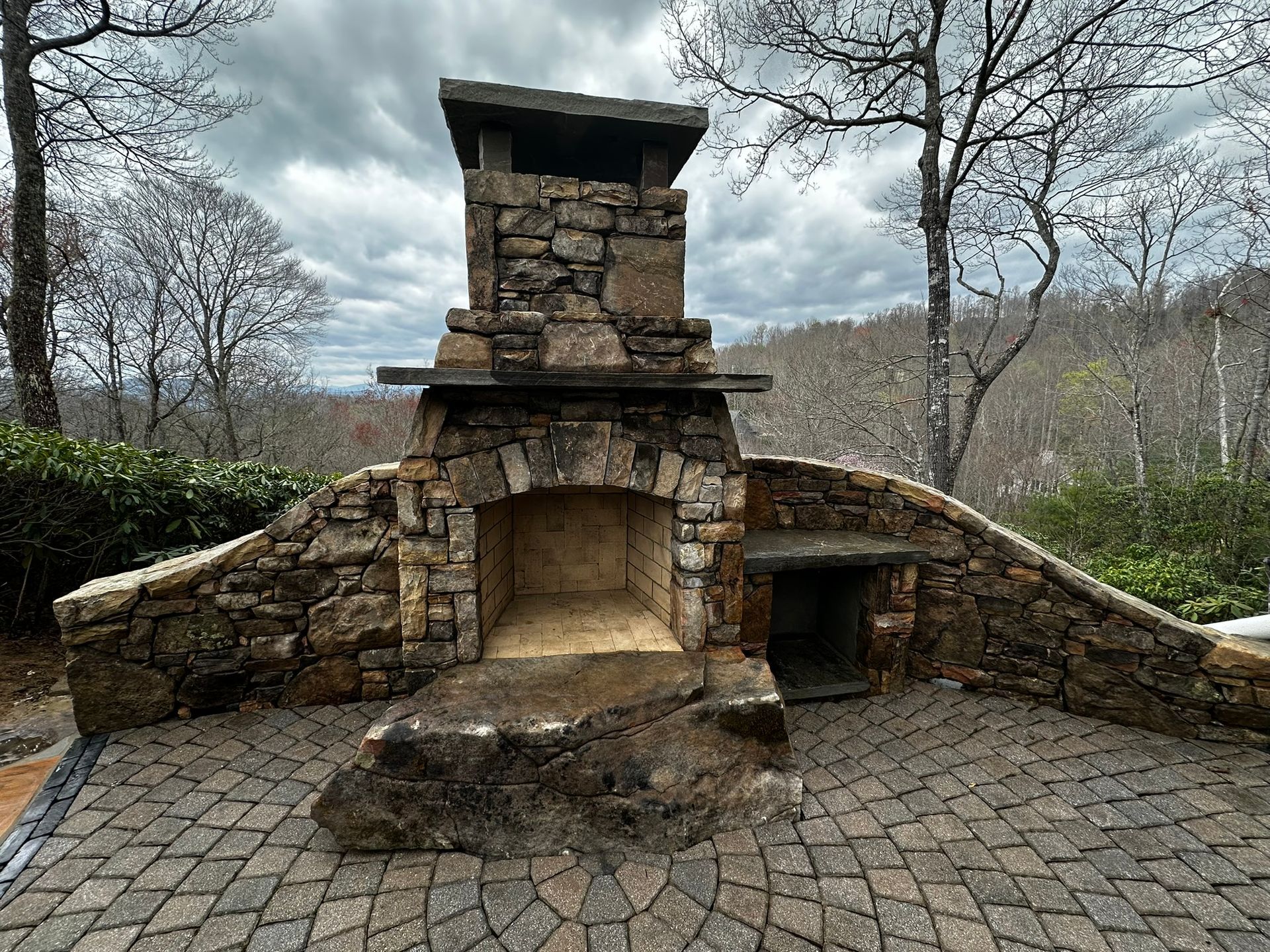 A stone fireplace is sitting on top of a brick patio.