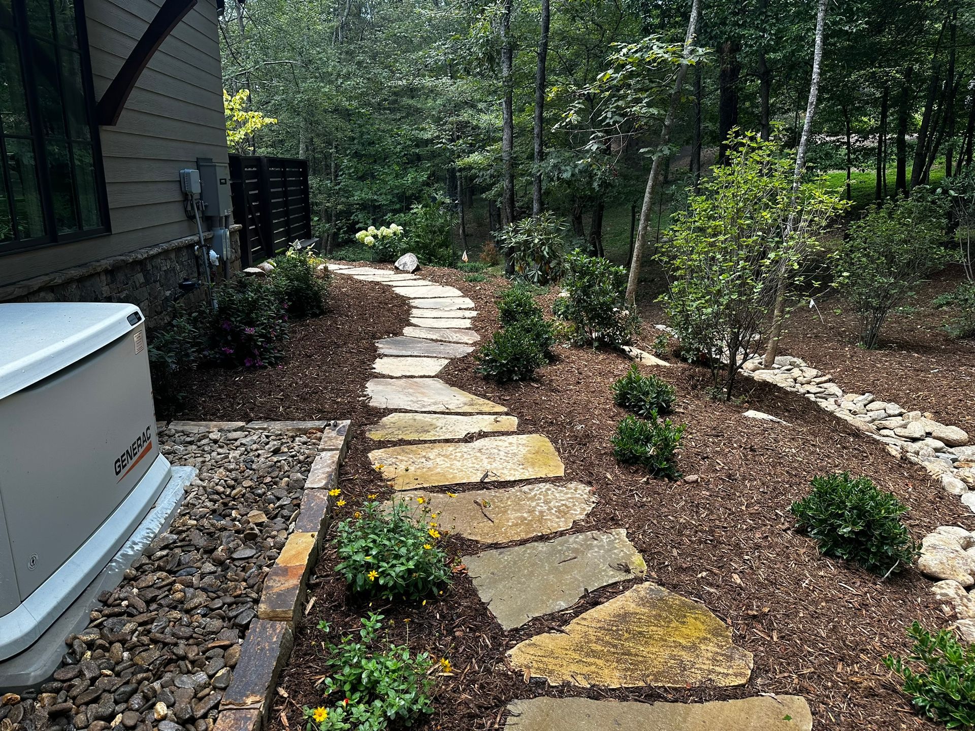 A stone walkway leading to a hot tub in a backyard.