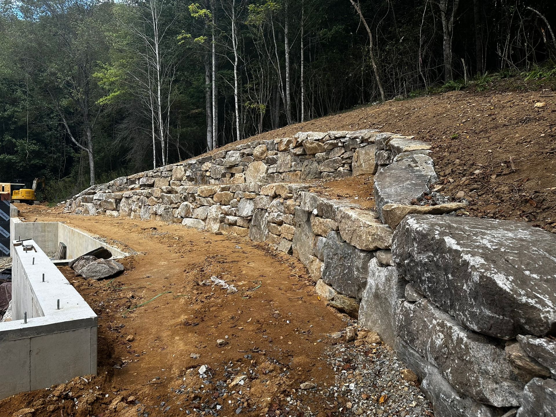 A large rock wall is being built on top of a dirt hill.
