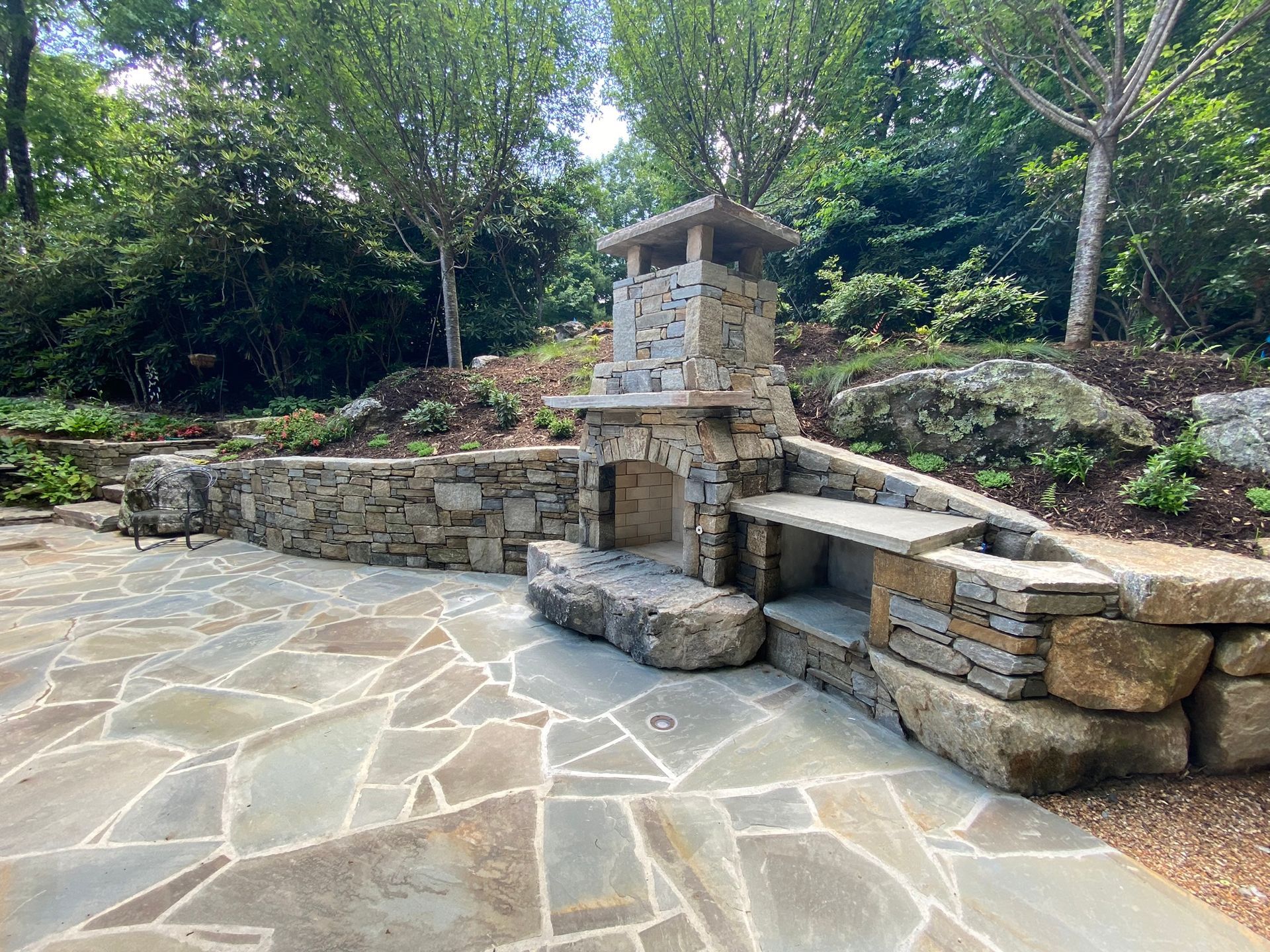 There is a stone fireplace in the middle of the patio.