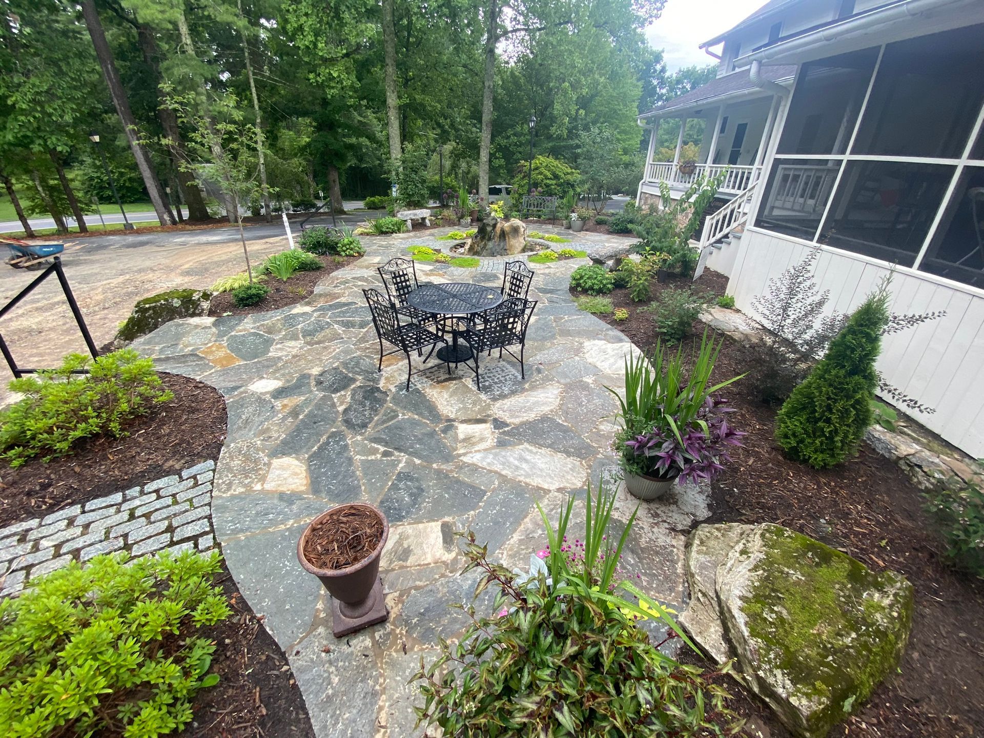 A patio with a table and chairs in front of a screened in porch.