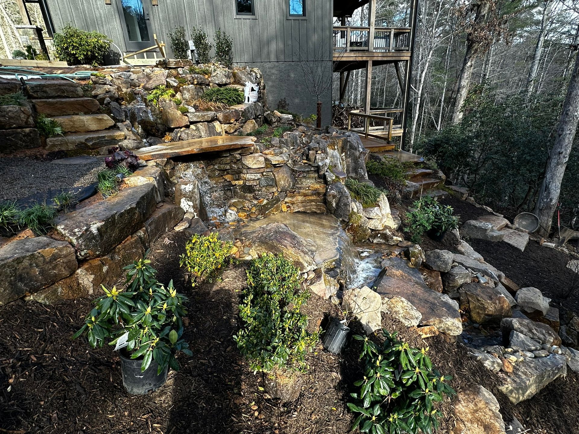 A waterfall is surrounded by rocks and plants in a backyard.