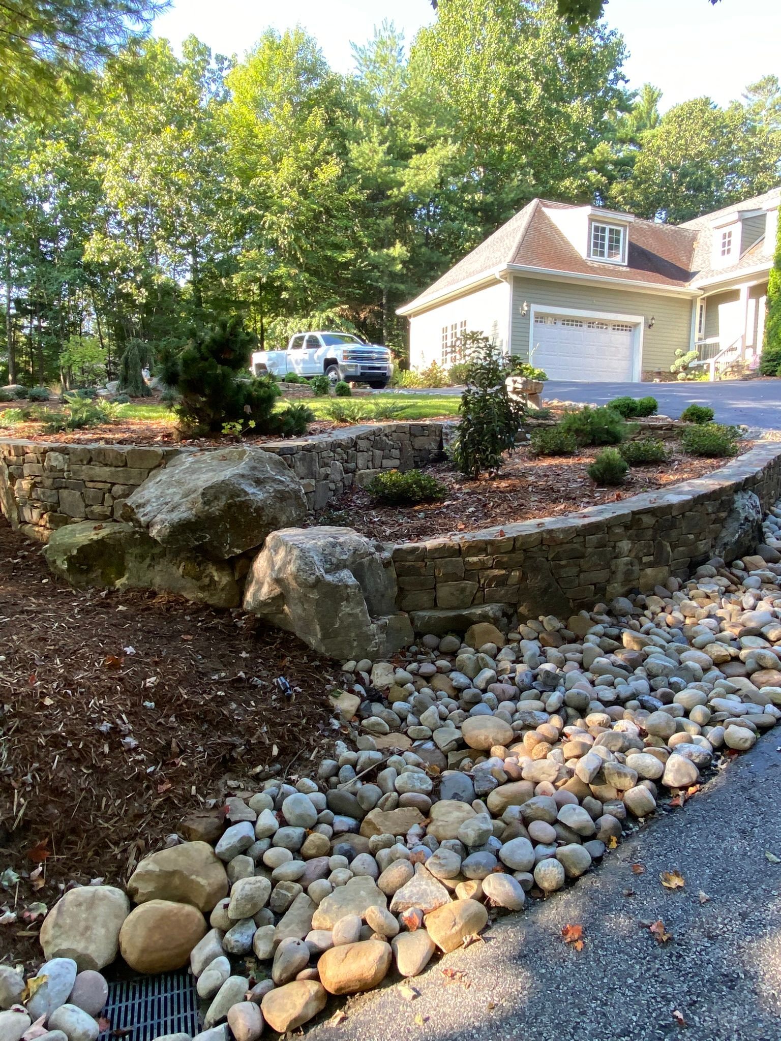 A house with a garage and a driveway surrounded by rocks and mulch.