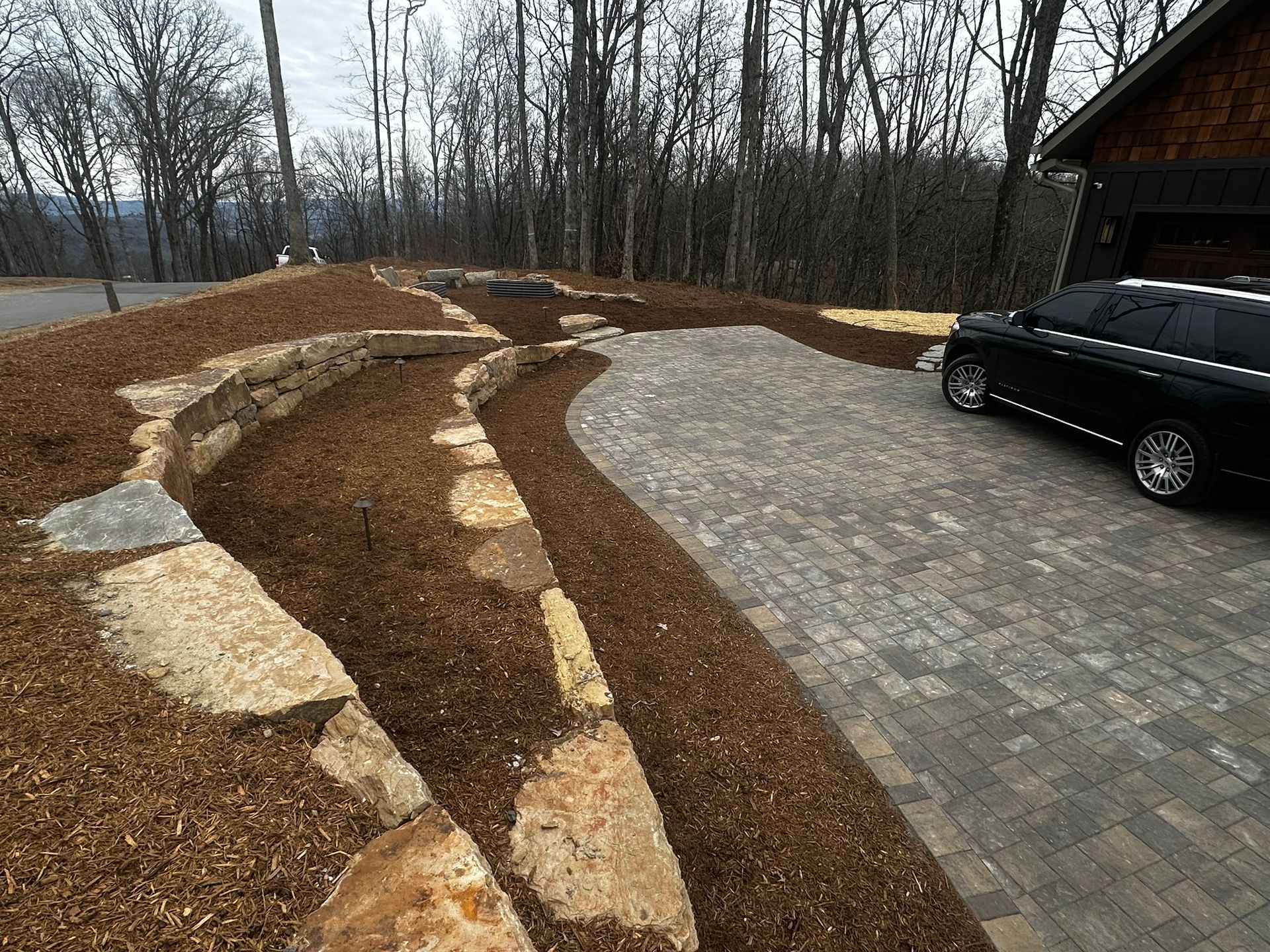 A black SUV is parked in a driveway next to a house.