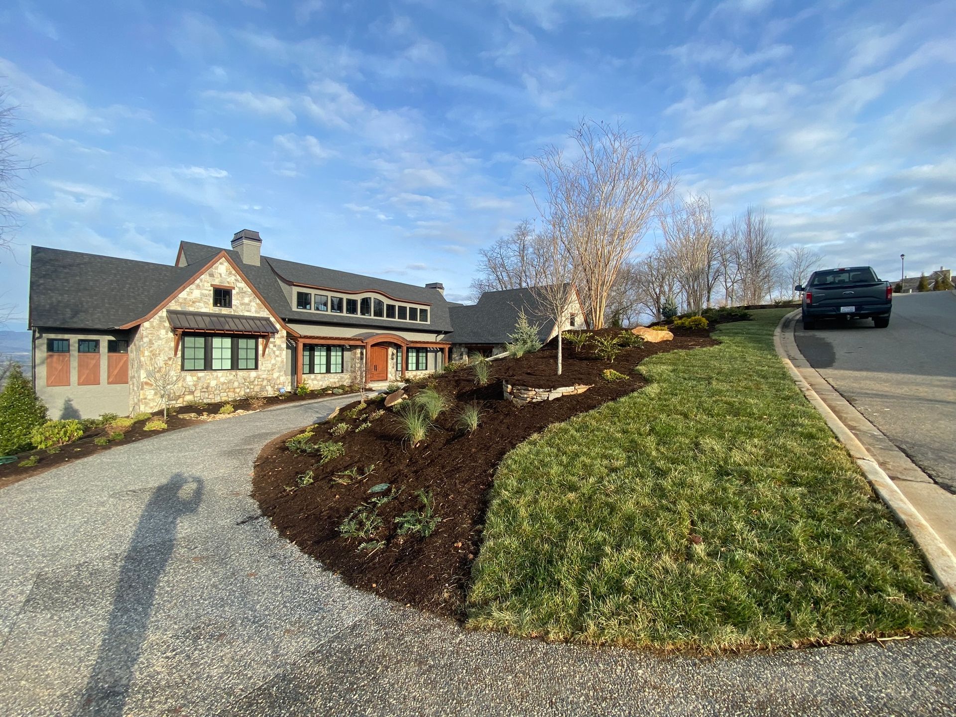A large house with a gravel driveway and a car parked in front of it.