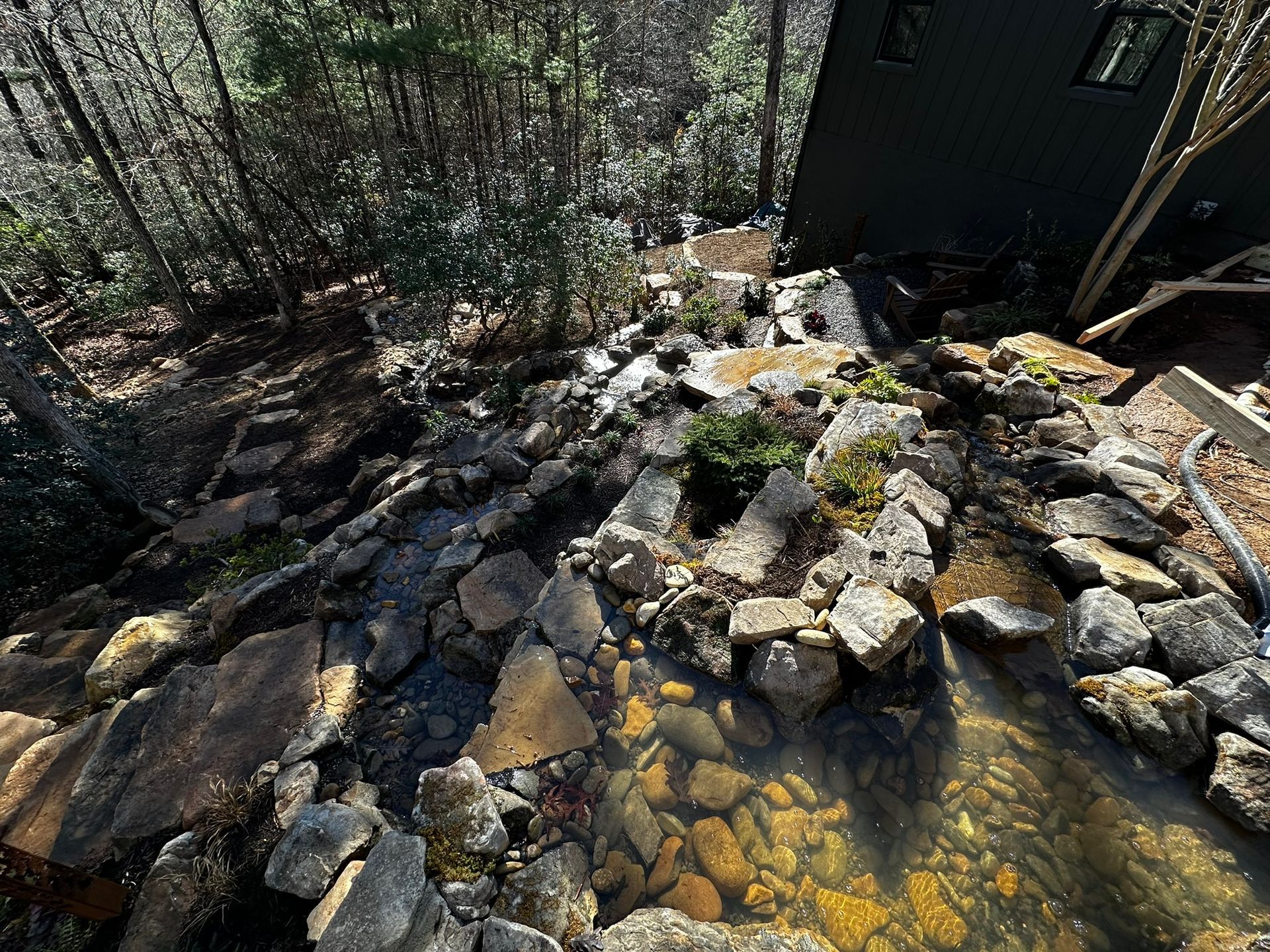 A small pond surrounded by rocks and trees in the woods.