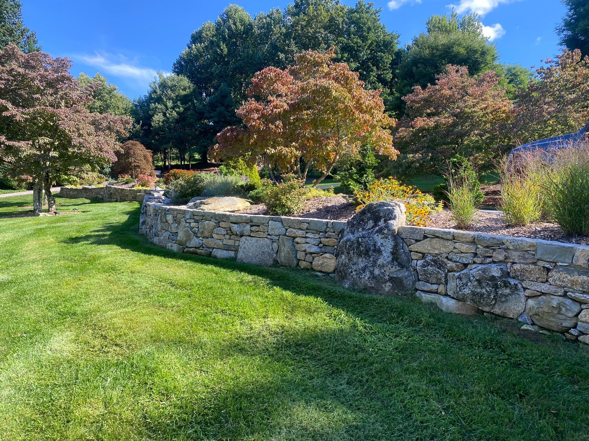 There is a stone wall in the middle of a lush green field.