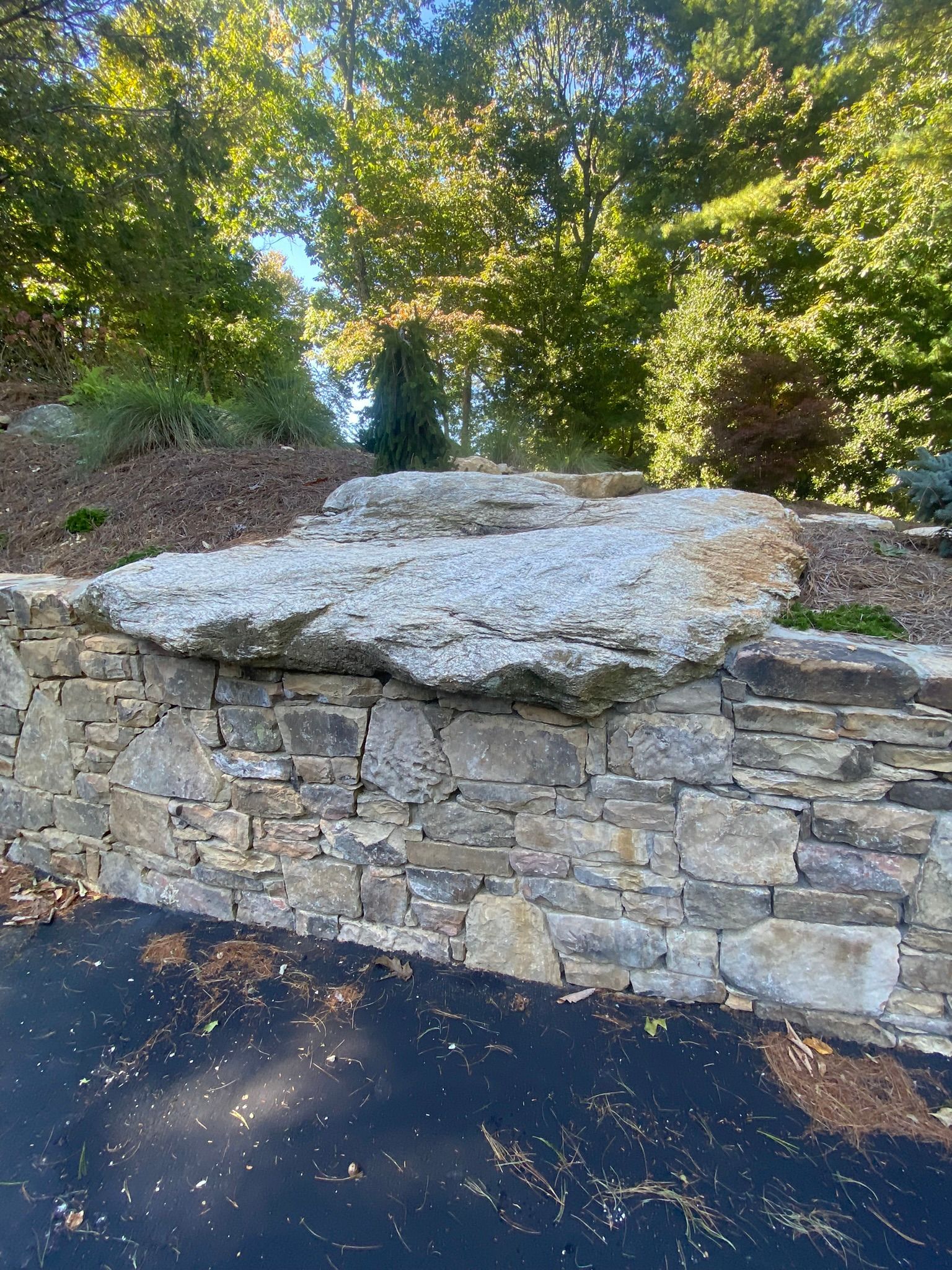 A large rock is sitting on top of a stone wall.