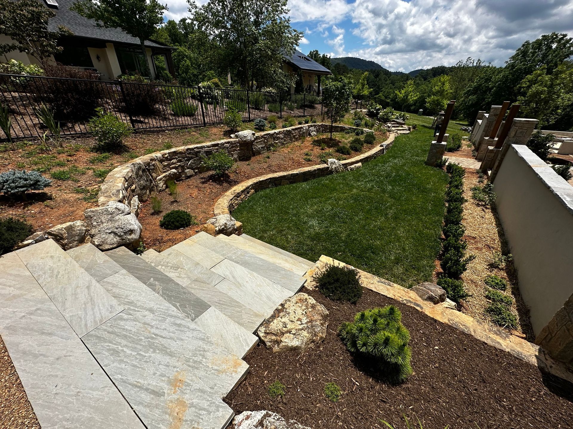 A lush green garden with stairs leading up to a house.