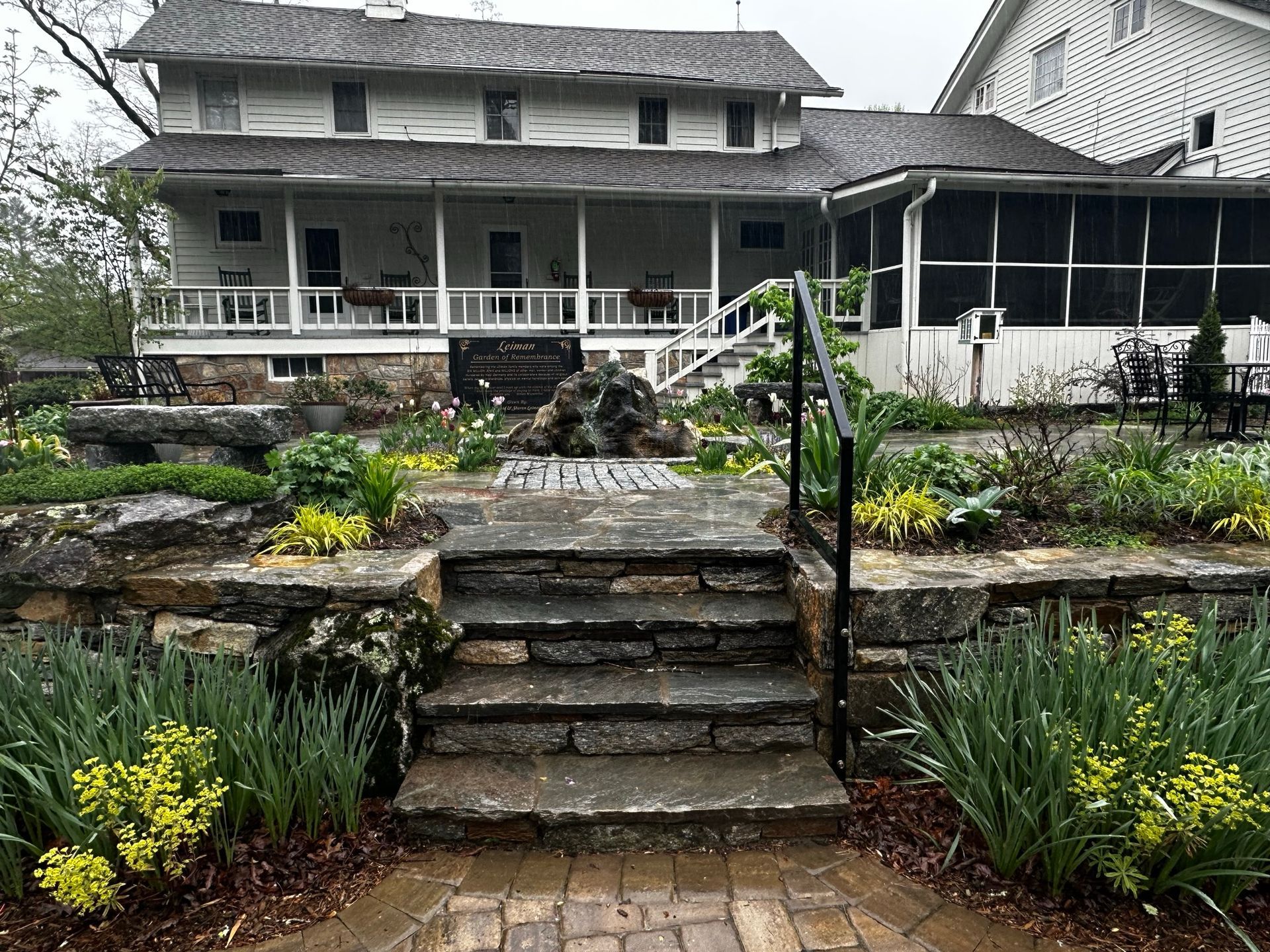 A large white house with a screened in porch and stairs leading up to it.