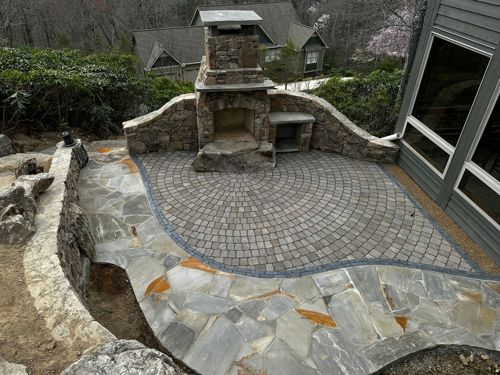 A stone patio with a fireplace in the middle of it.