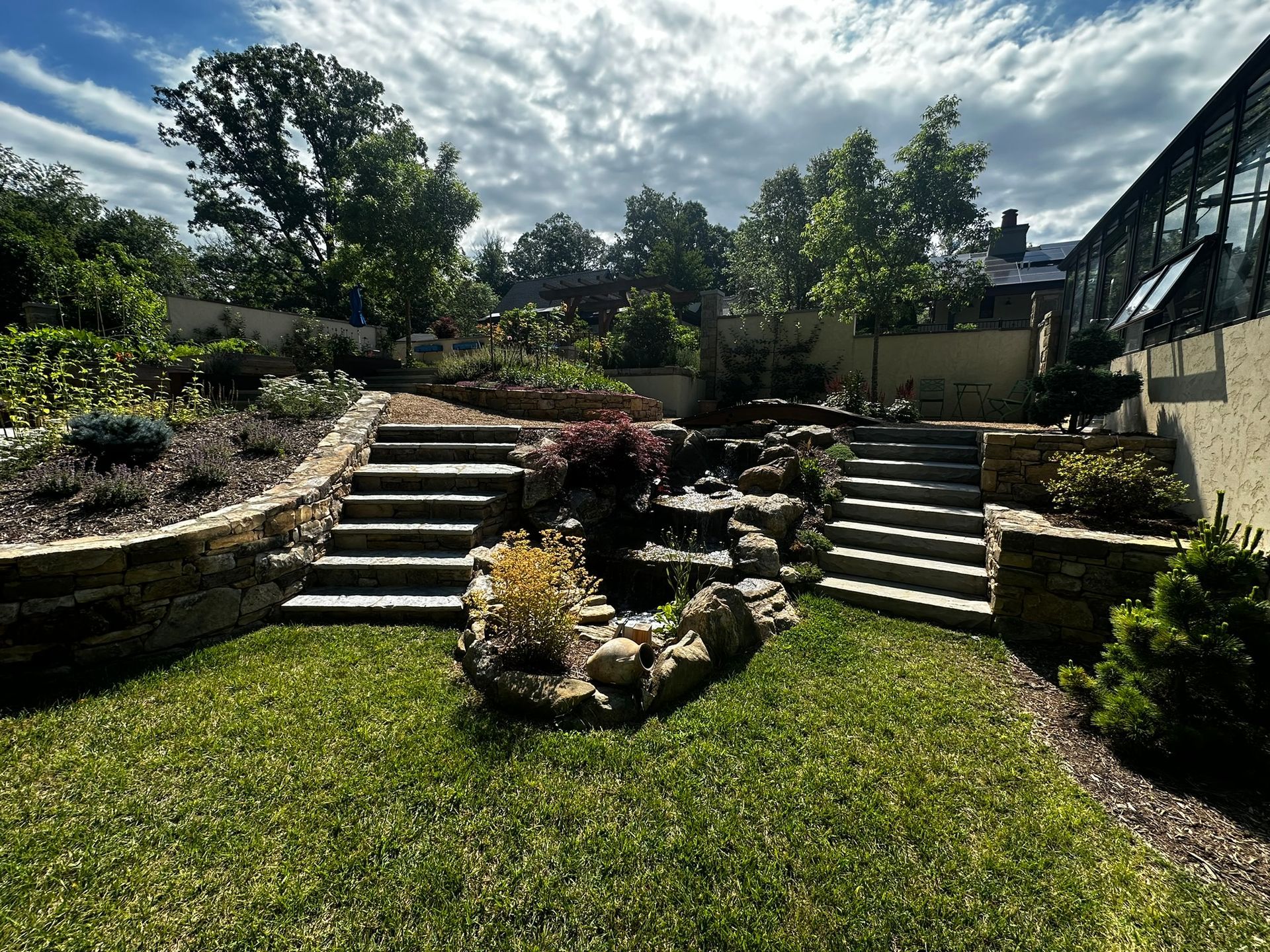 A lush green yard with stairs leading up to a house.