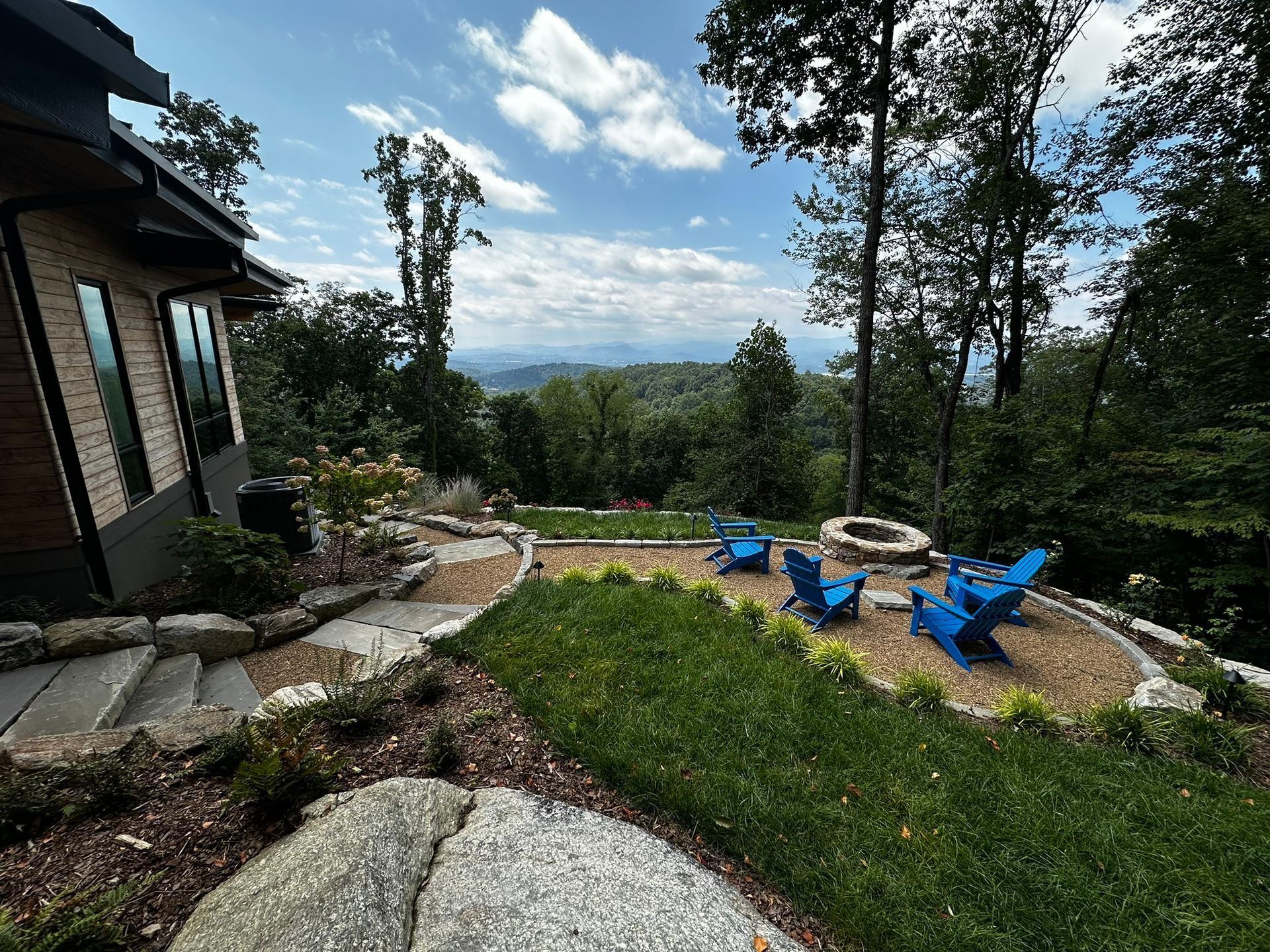 There is a fire pit in the backyard of a house with a view of the mountains.