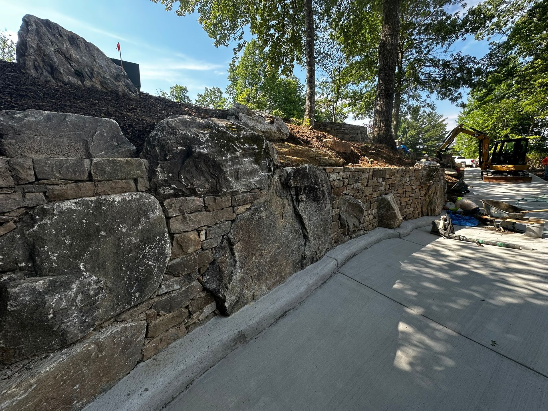 A stone wall is being built on the side of a road.