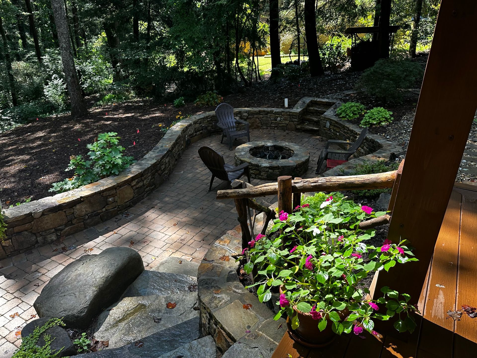 A patio with a fire pit and chairs in the woods.