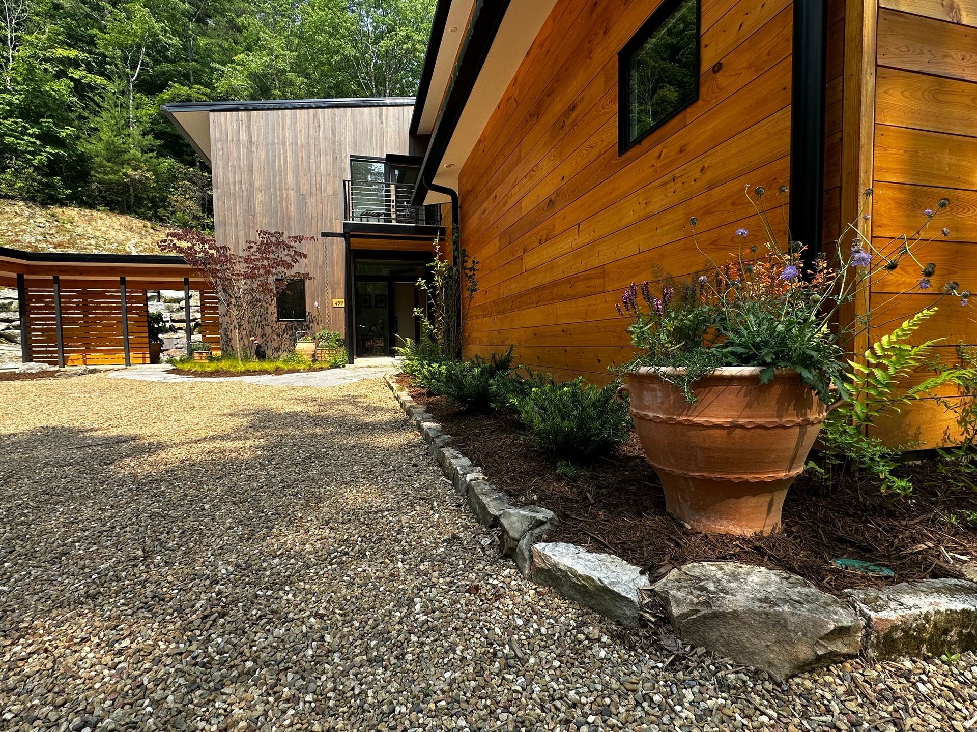 A large wooden house with a gravel driveway leading to it.
