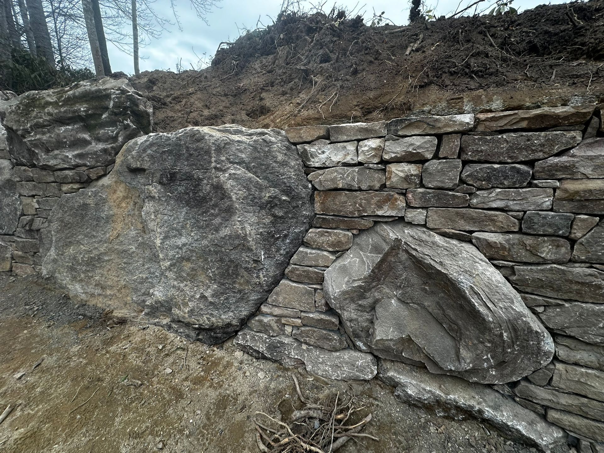 A large rock is sitting on top of a stone wall.