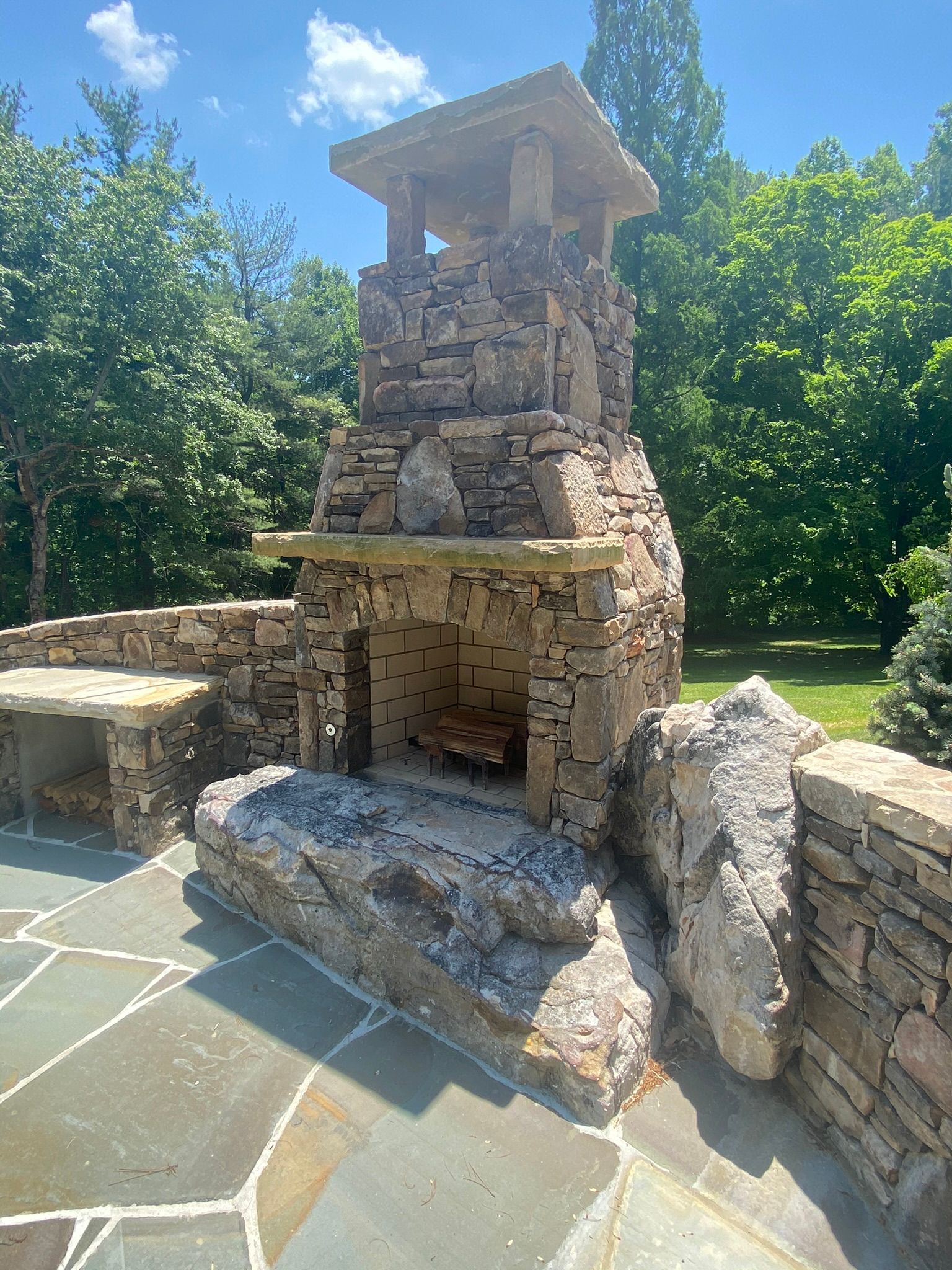 A stone fireplace is sitting on top of a stone patio.