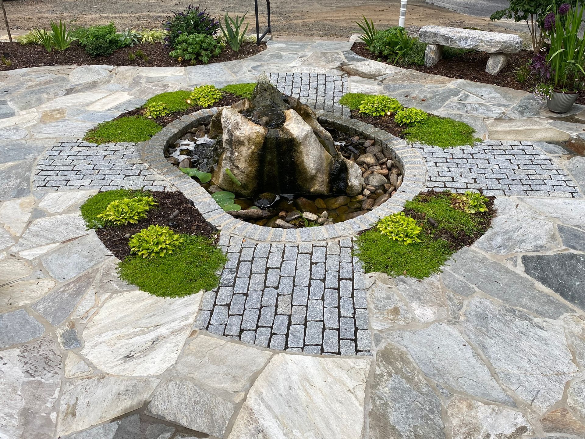 A stone patio with a fountain in the middle of it.