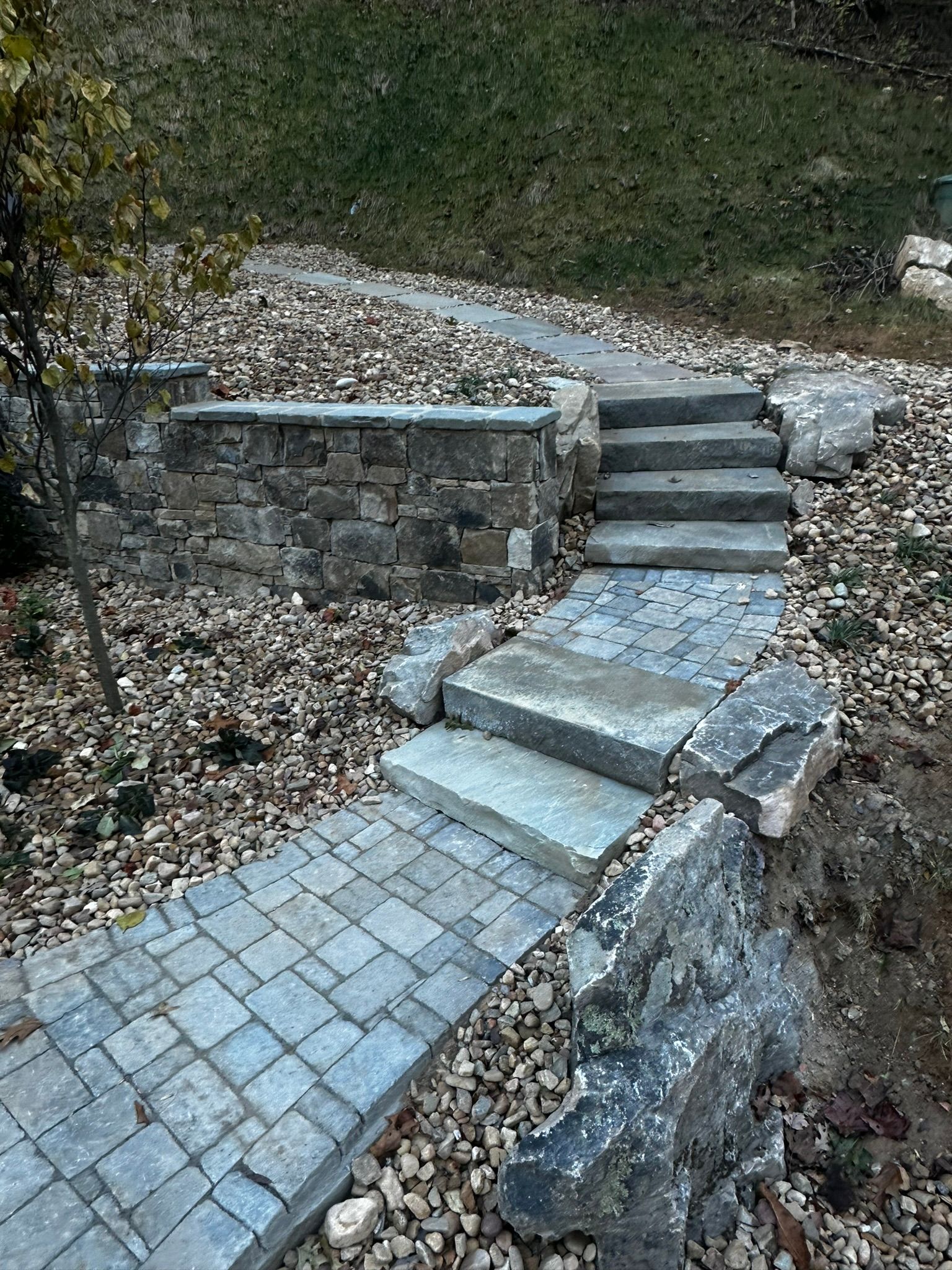 A stone walkway with stairs leading up to a stone wall.