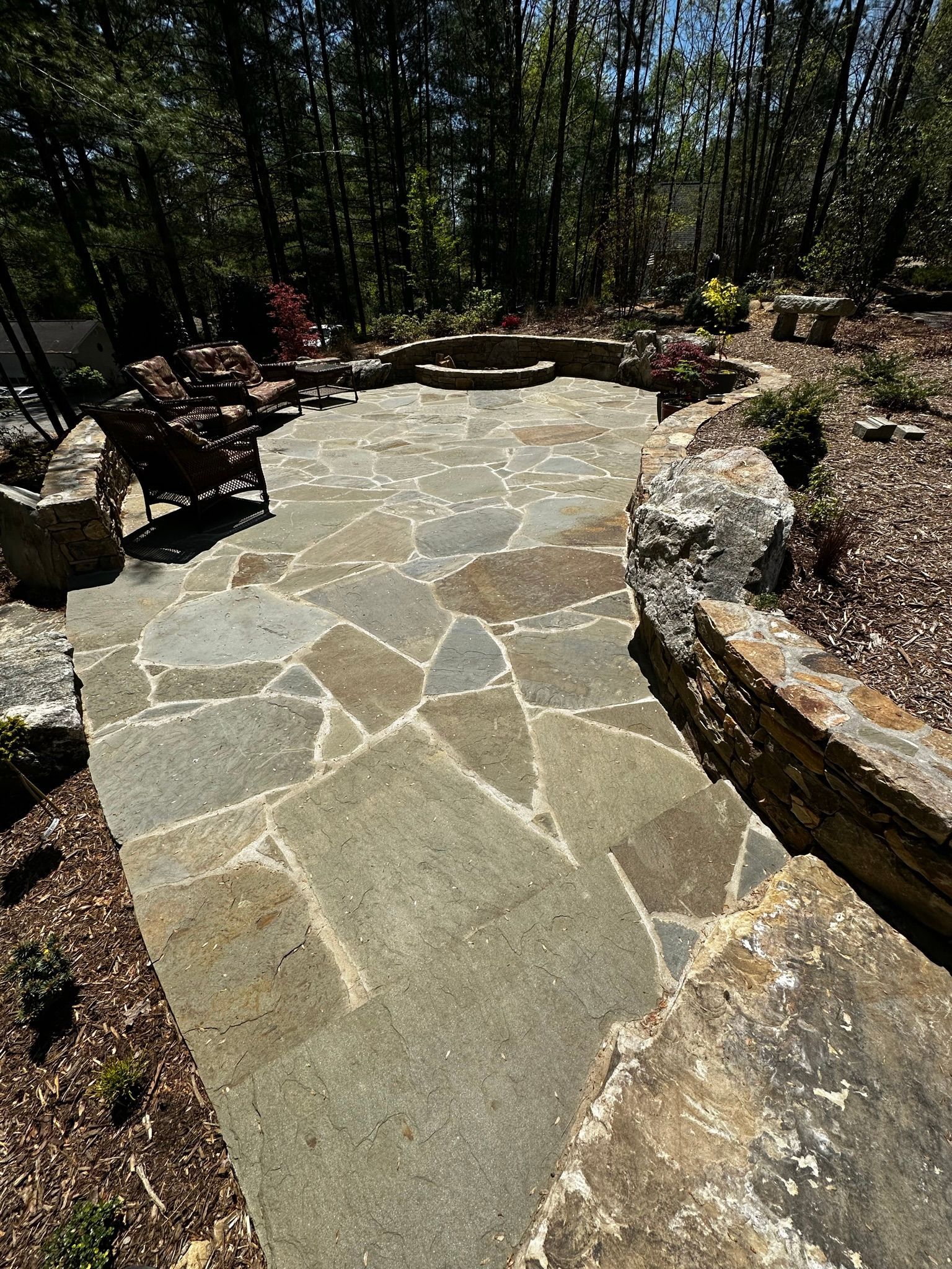 A stone walkway leading to a patio in the woods.