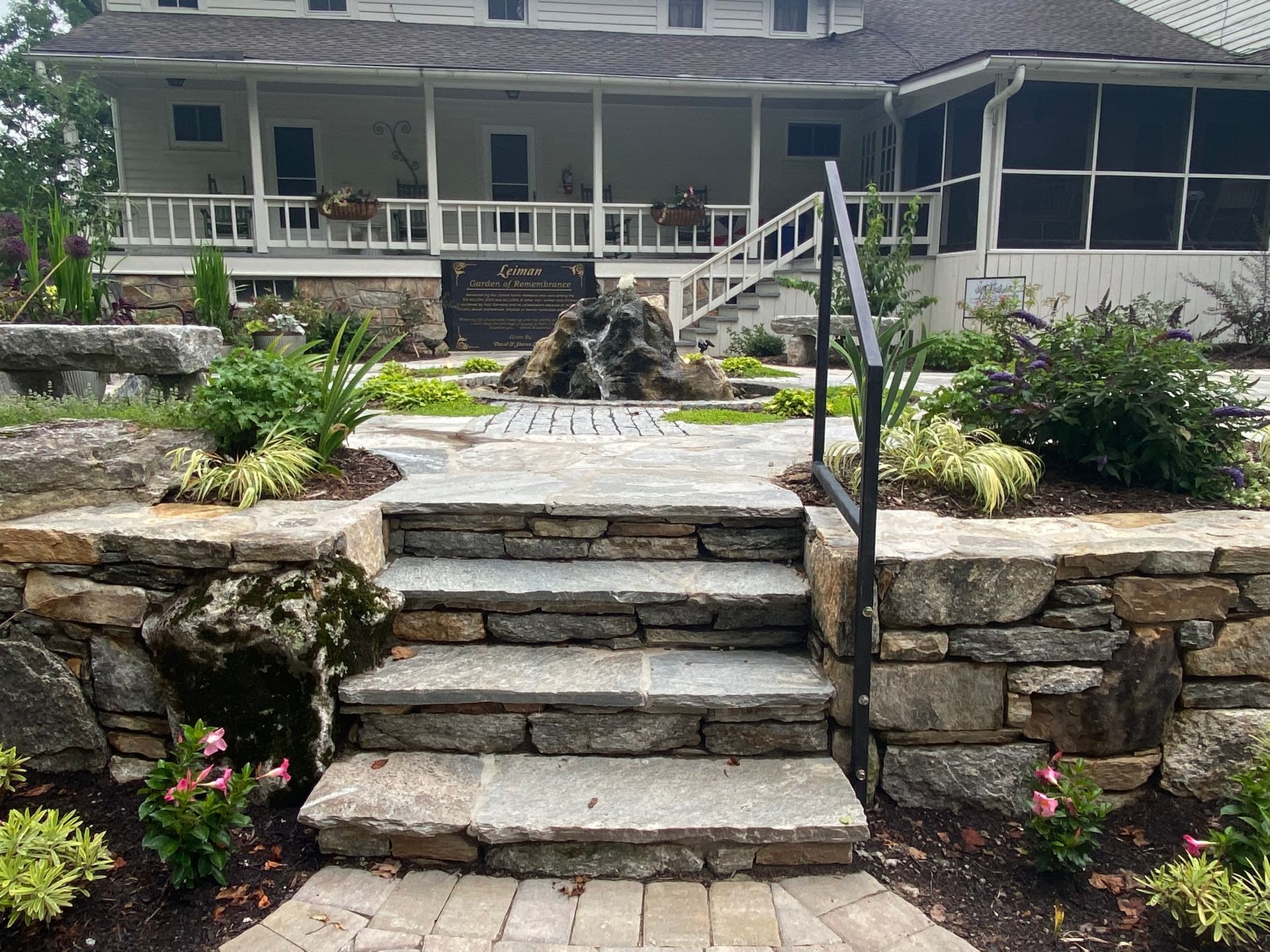 A stone staircase leading up to a house with a screened in porch.