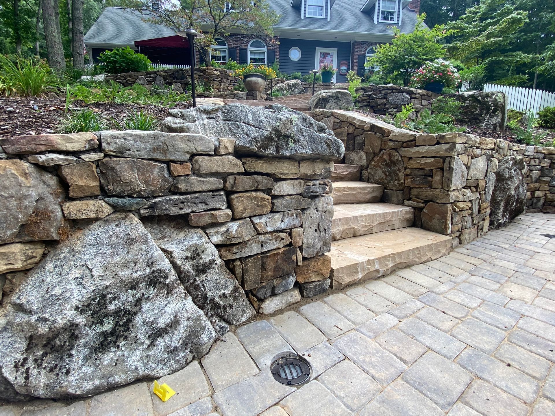 A stone wall with stairs leading up to a house.