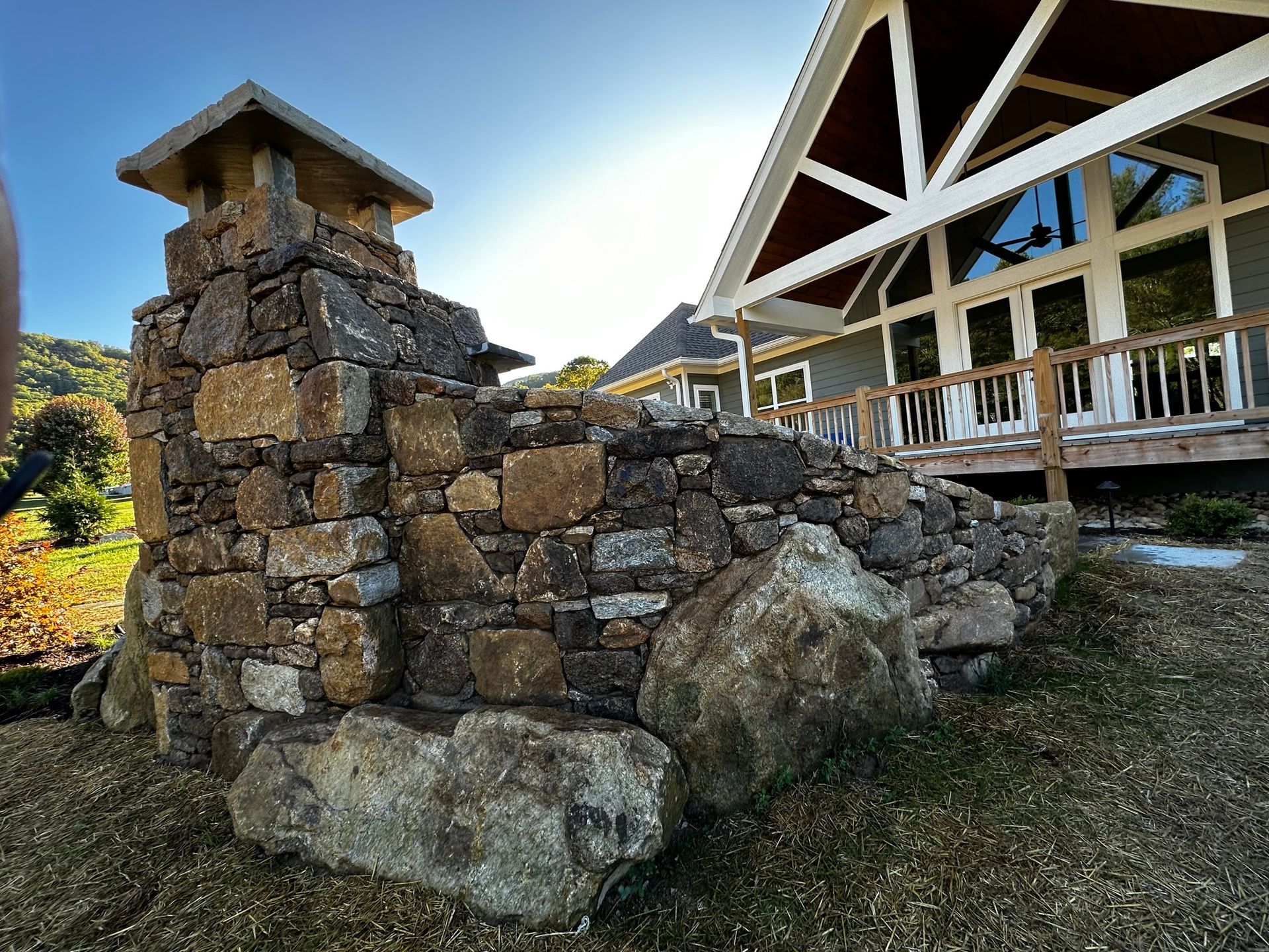 A stone wall with a chimney on top of it in front of a house.