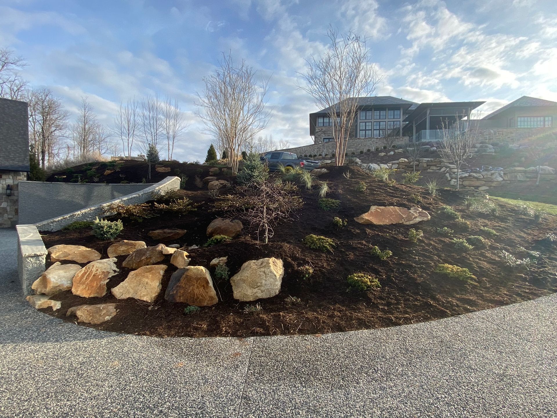 A large rock garden with a house in the background.