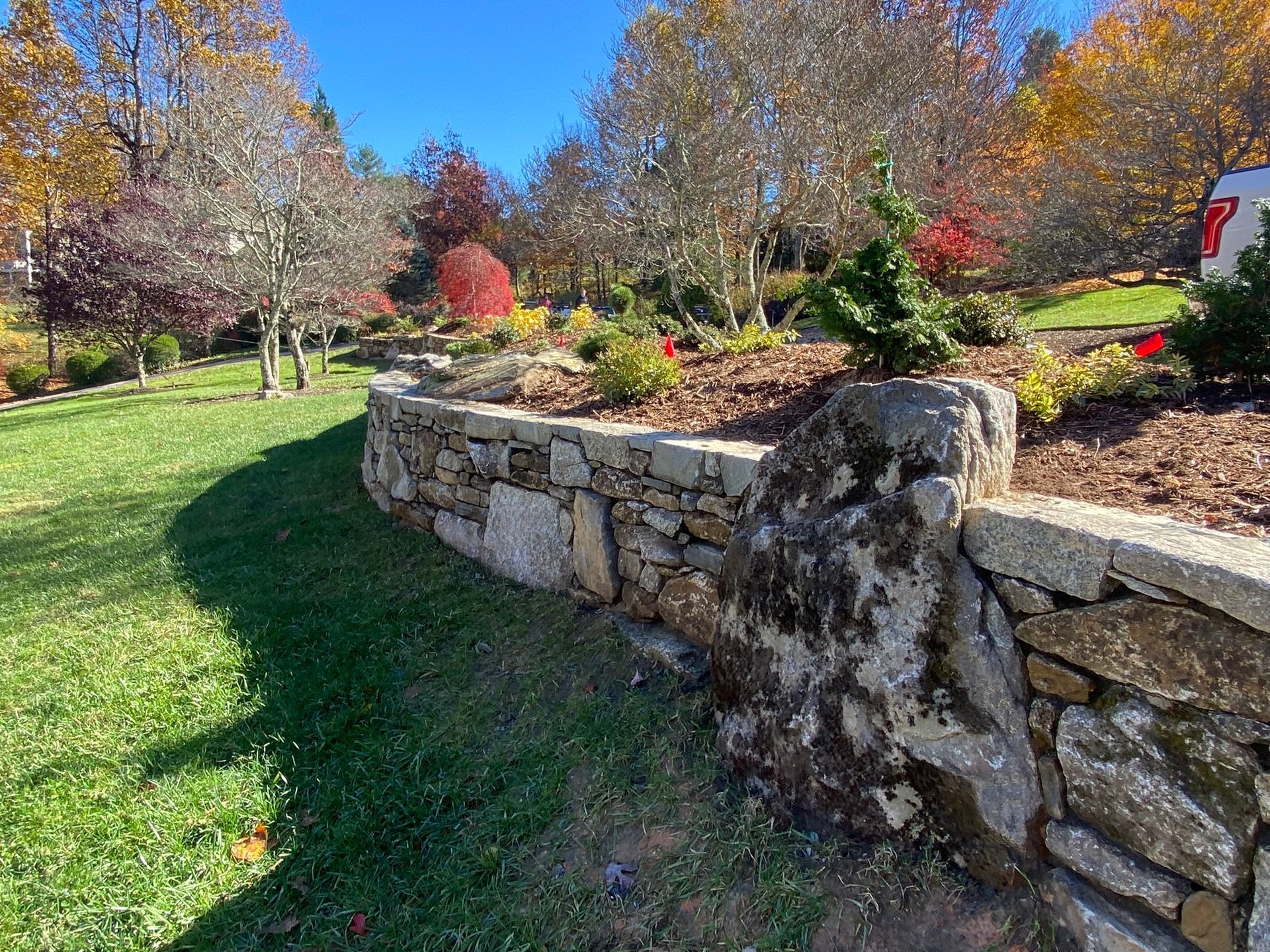 There is a stone wall in the middle of a lush green field.