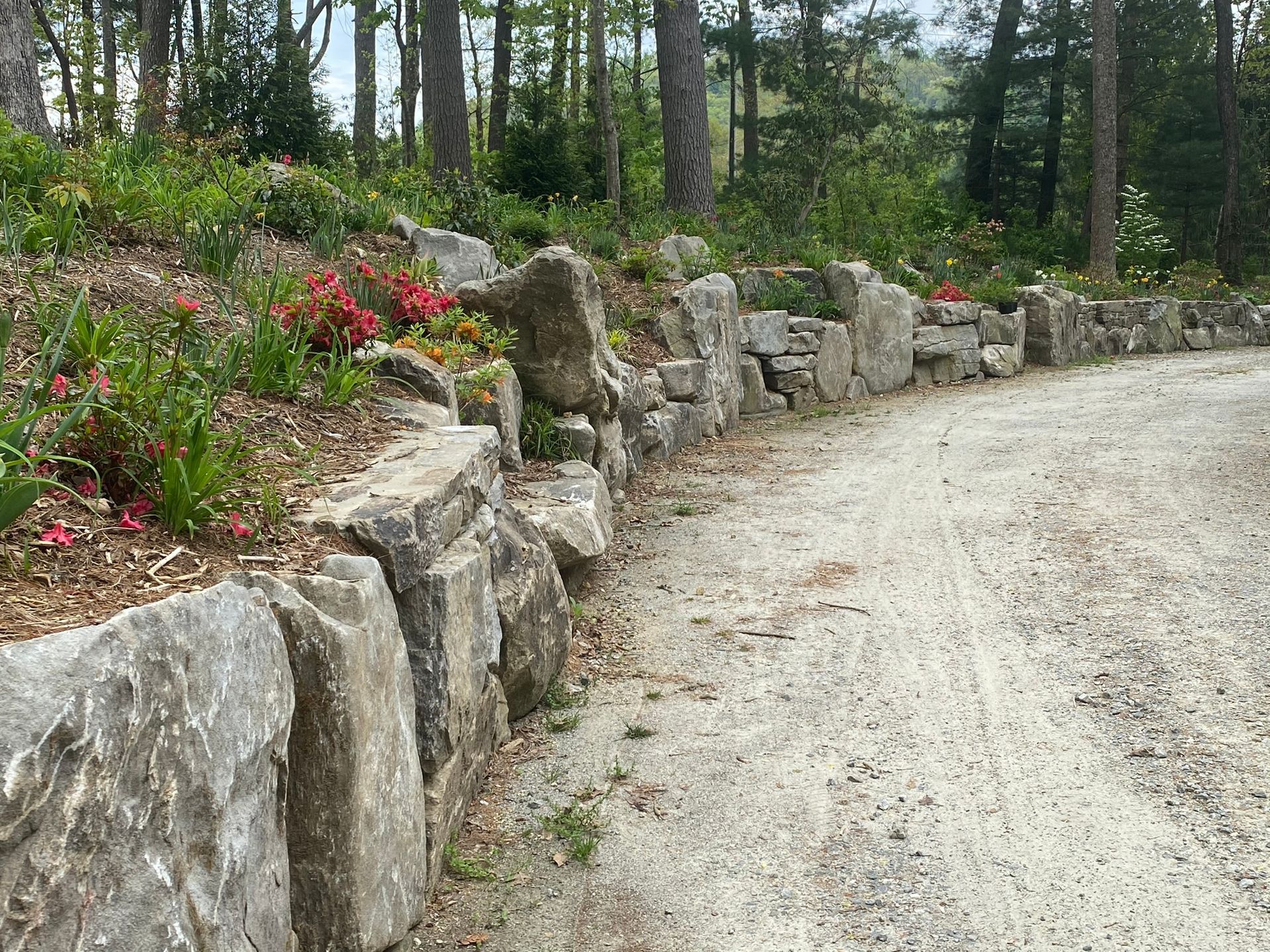 A dirt road with a stone wall on the side of it.