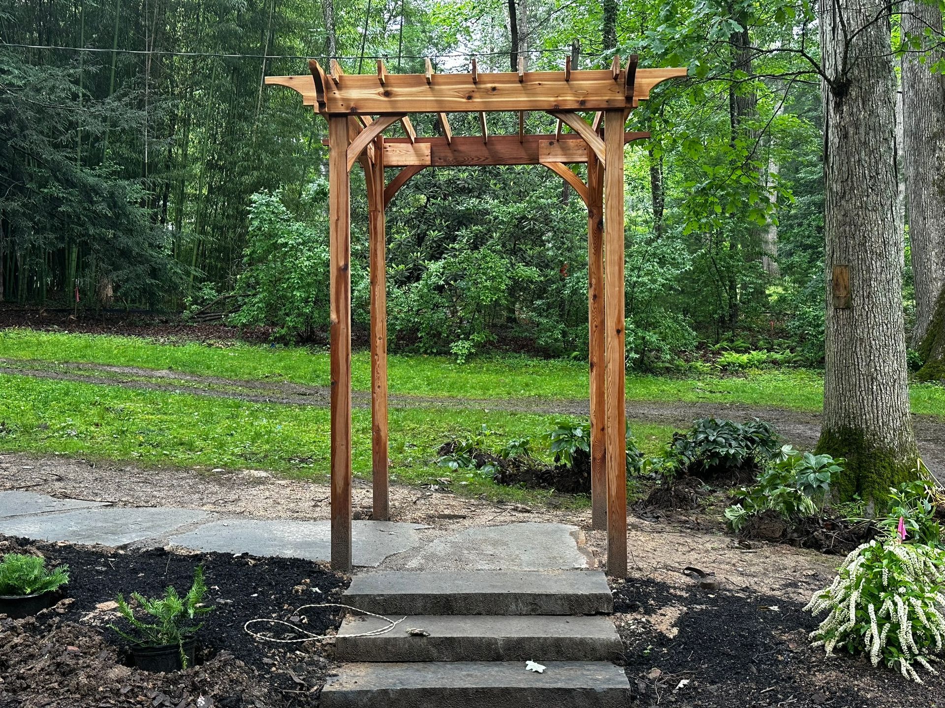 A wooden archway with steps leading to it in a park.