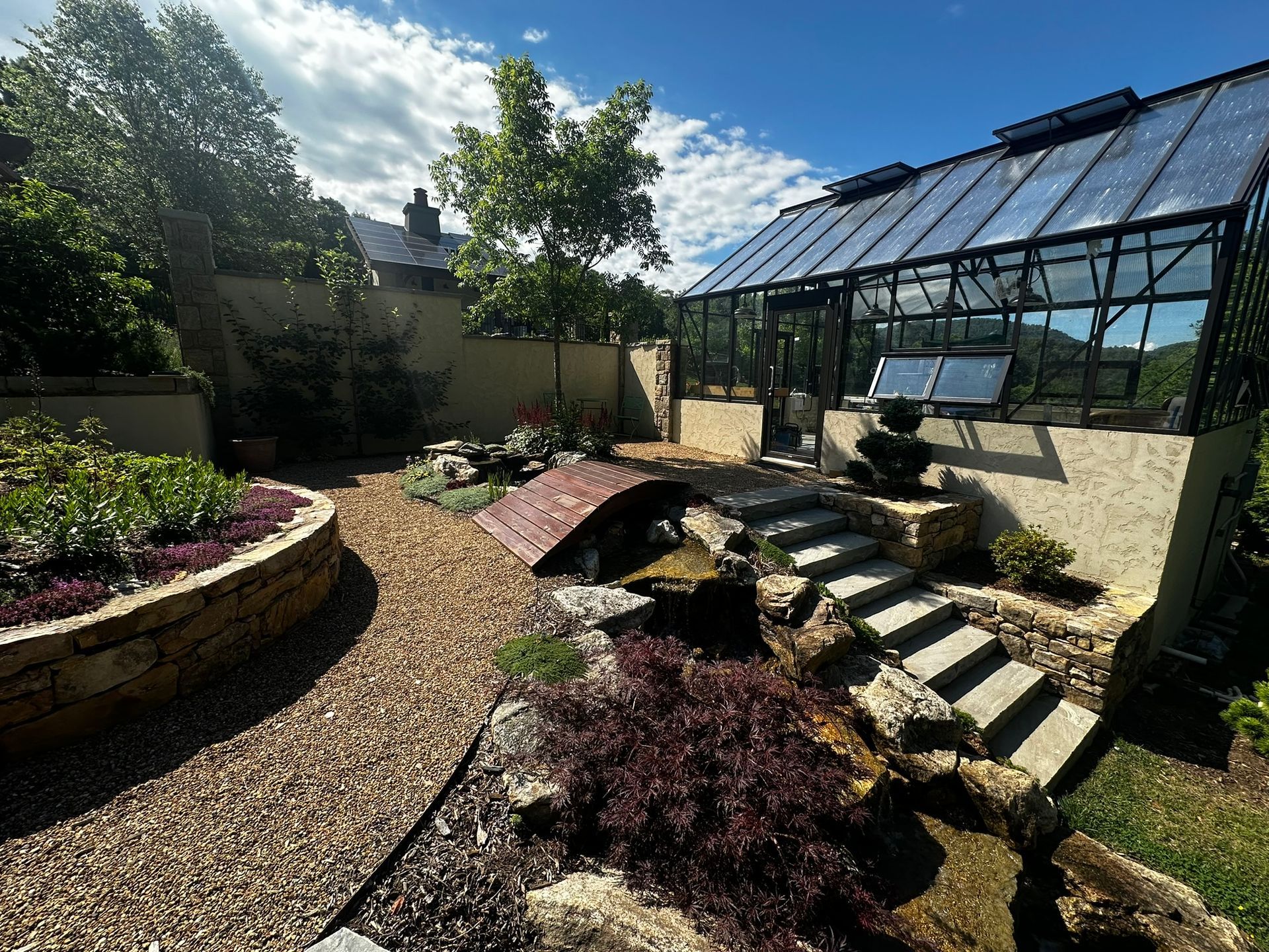 A garden with a greenhouse in the background.