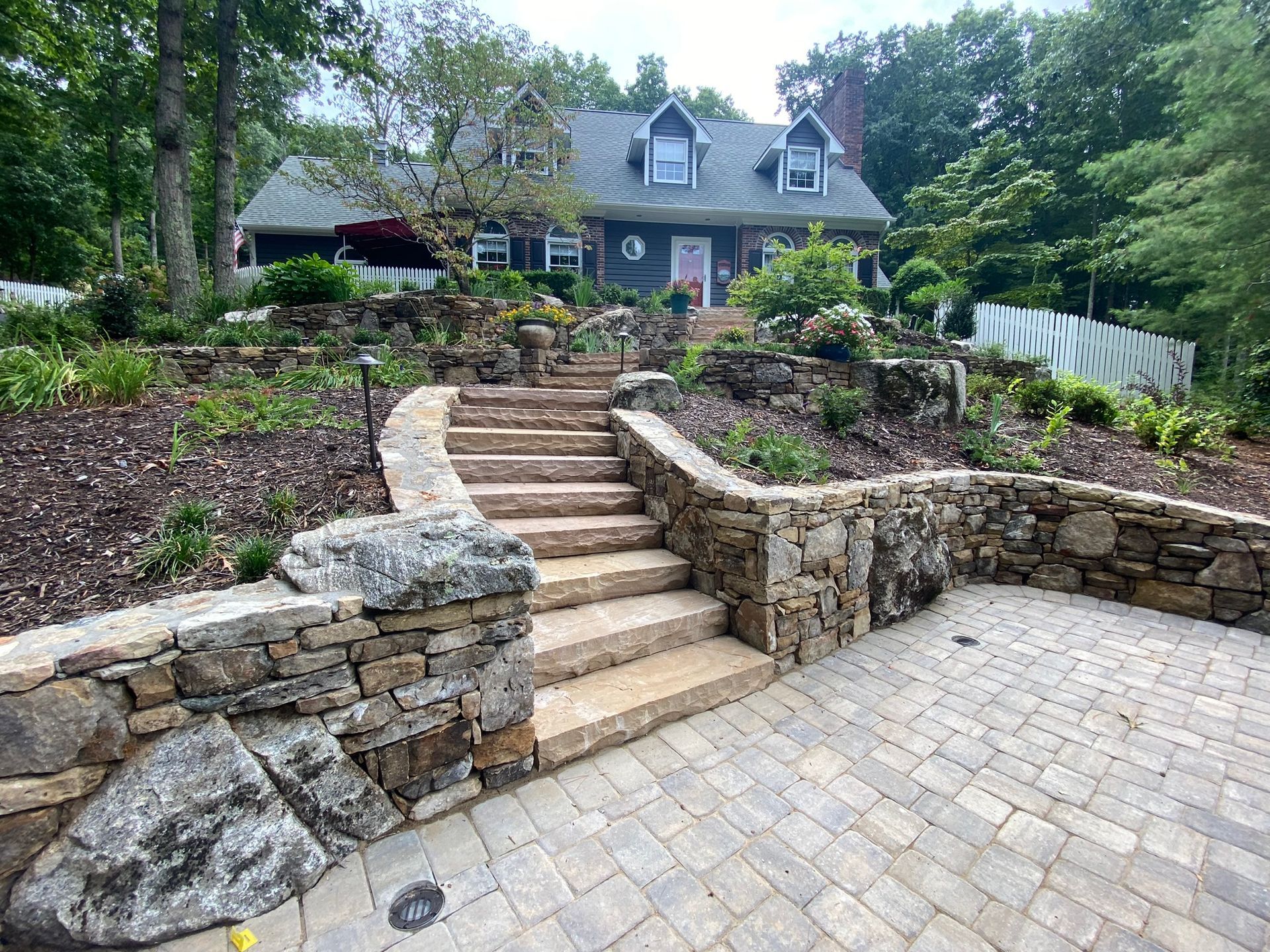 A stone wall with stairs leading up to a house.