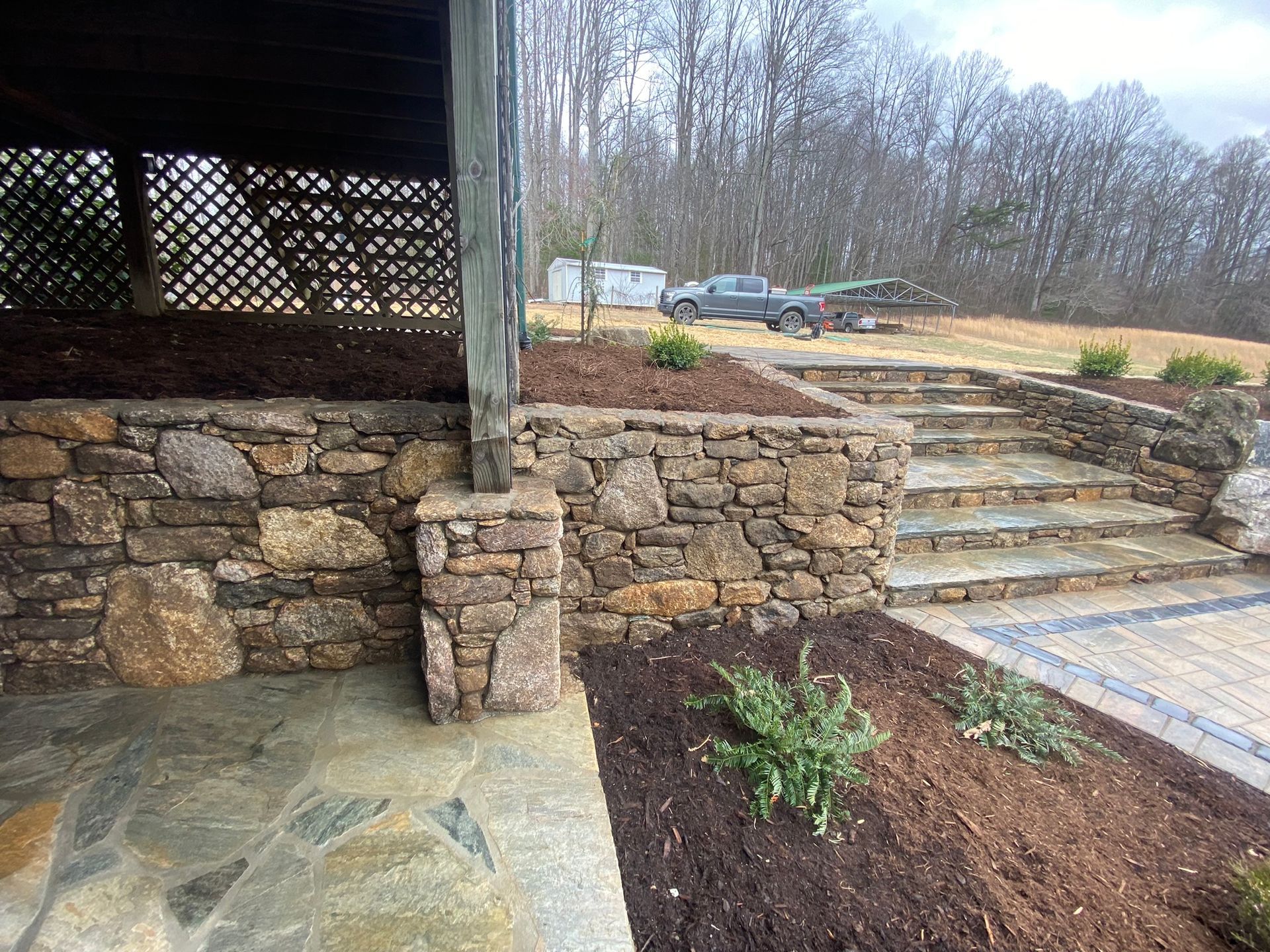 A stone wall with stairs leading up to it in a garden.