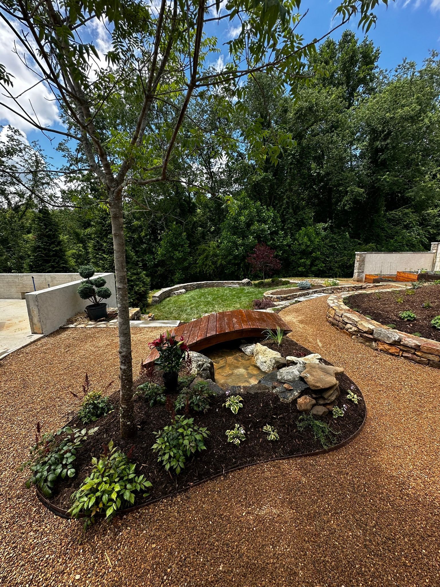 A garden with a pond and a bridge in the middle of it.