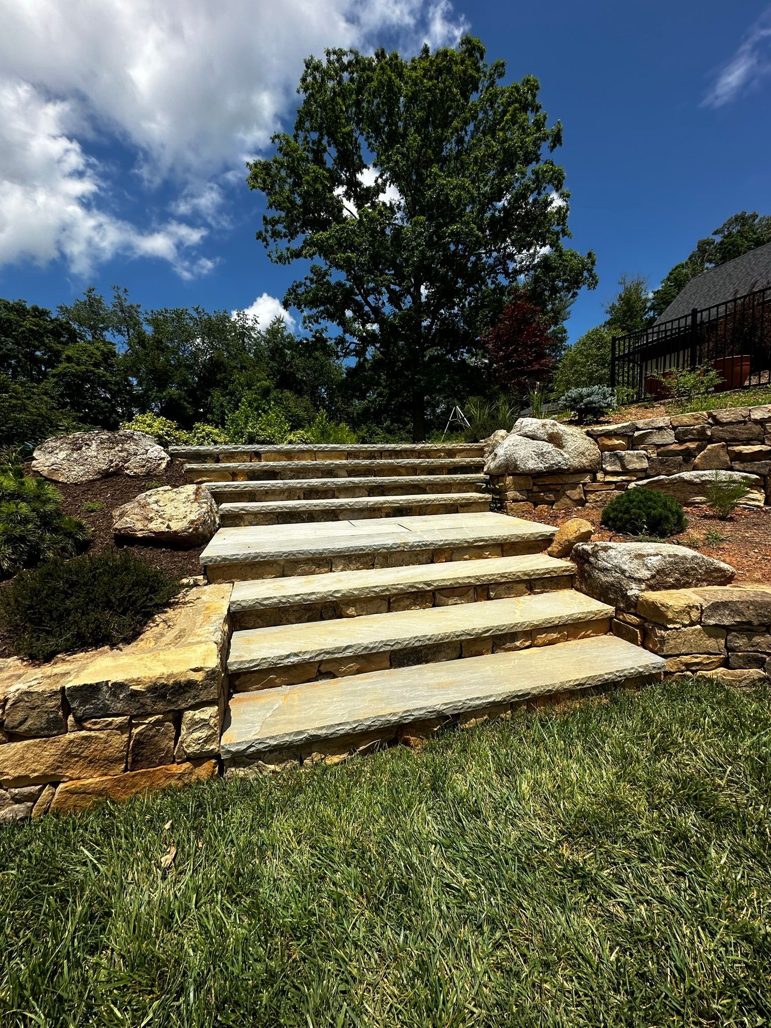 A set of stone stairs leading up to a lush green hillside.