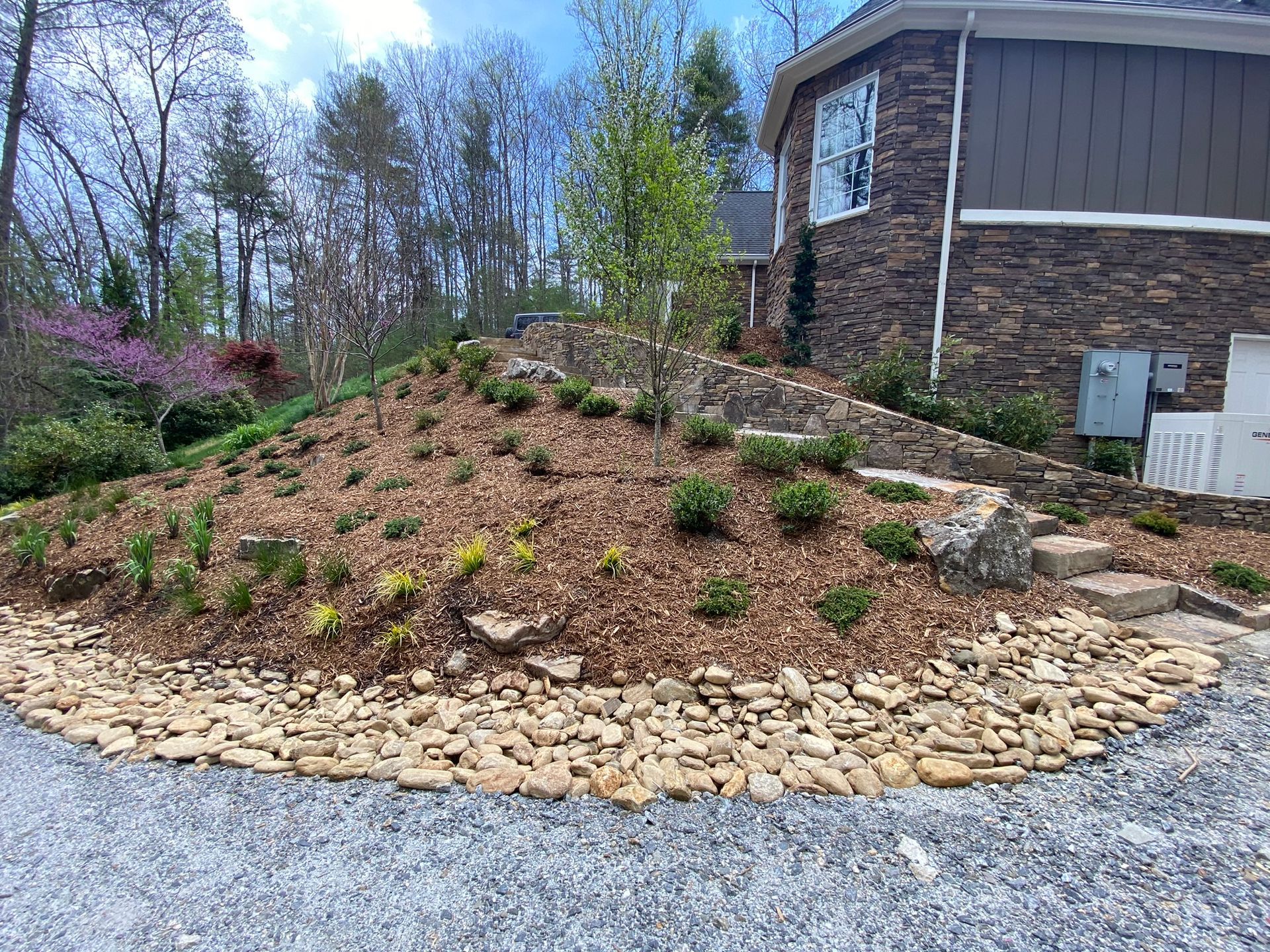 A house with a lot of rocks and plants in front of it.