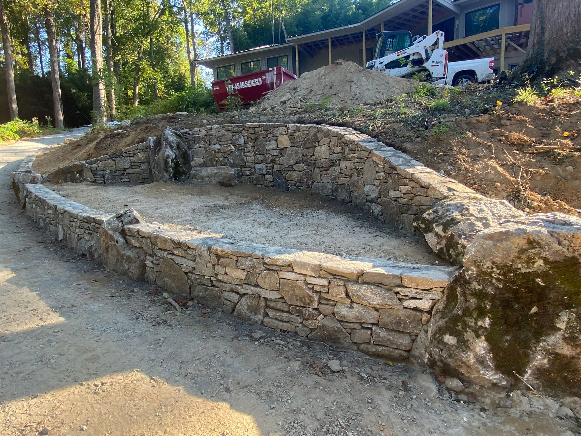 A large stone wall is being built in front of a house.