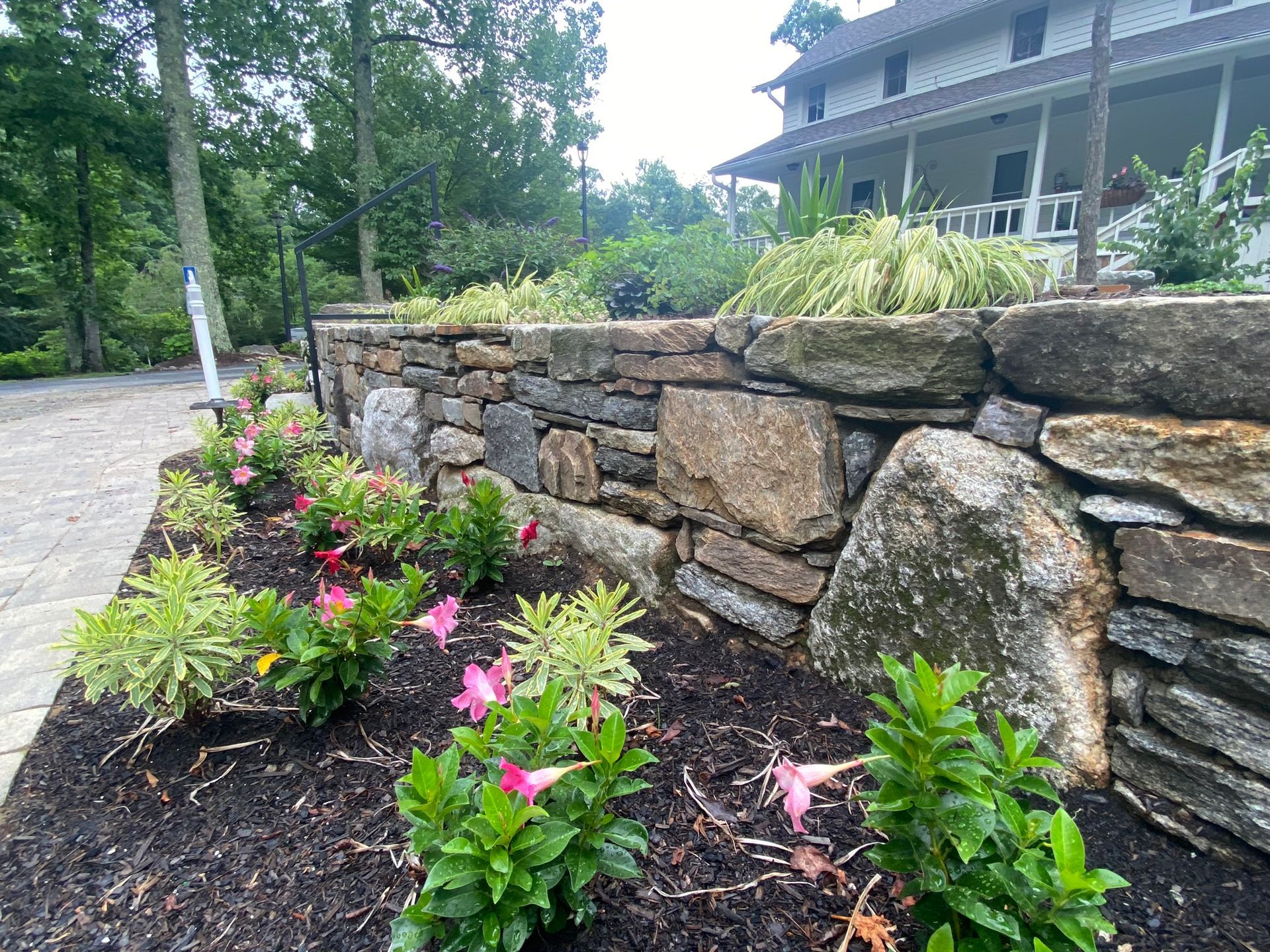 A stone wall with flowers in front of a house.