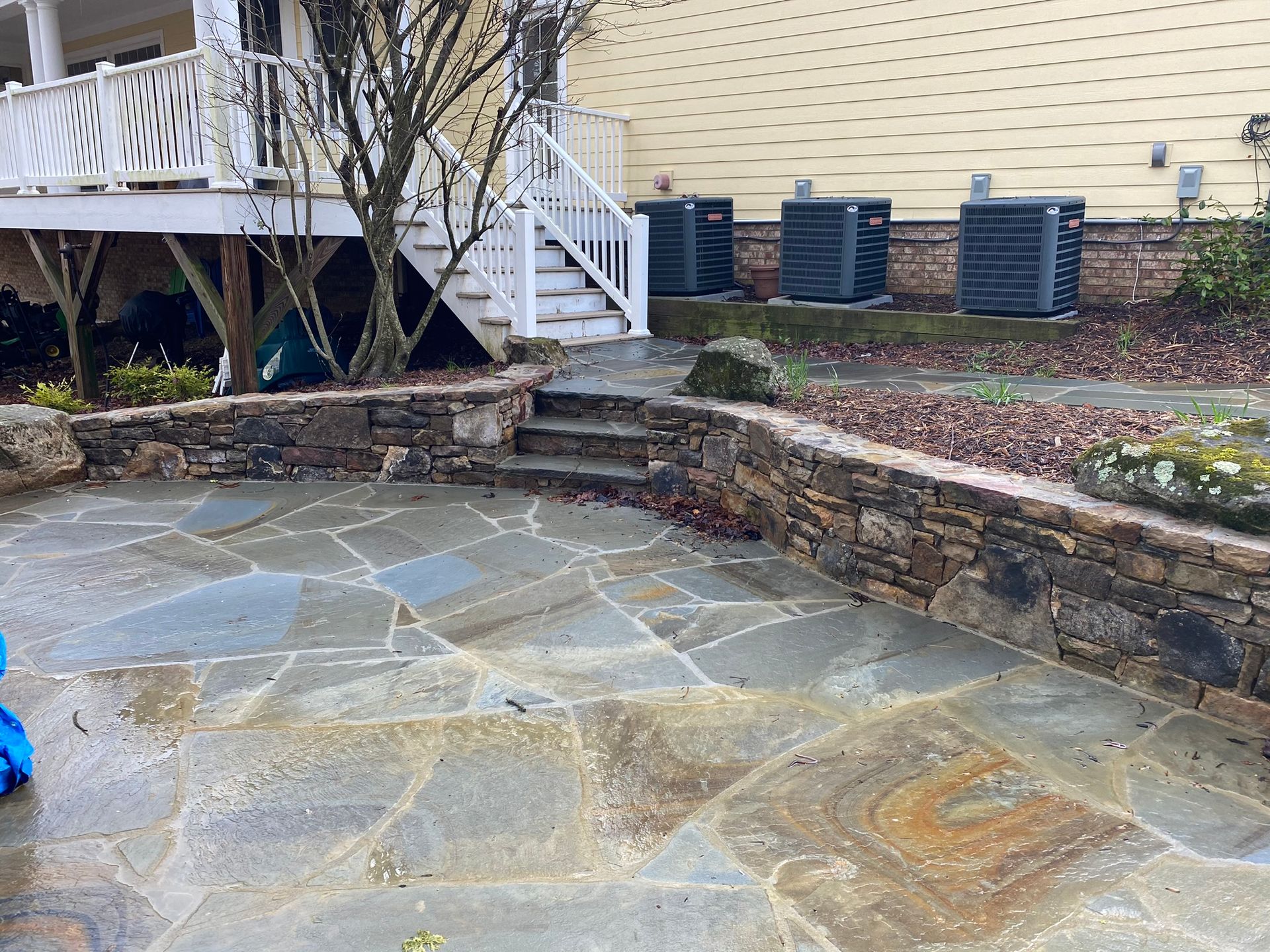 A stone patio with stairs leading up to a house.