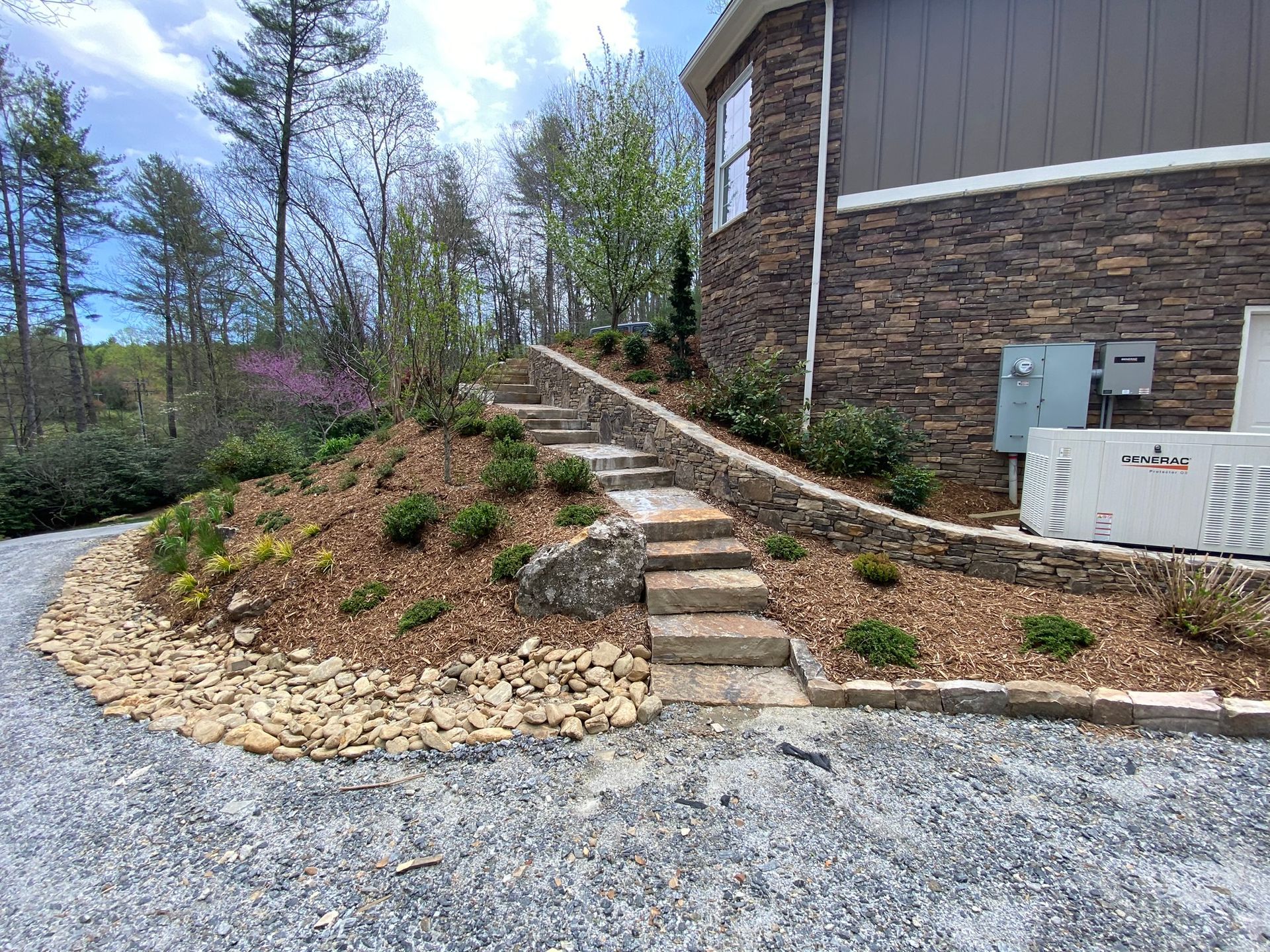 A house with stairs leading up to it and a gravel driveway.