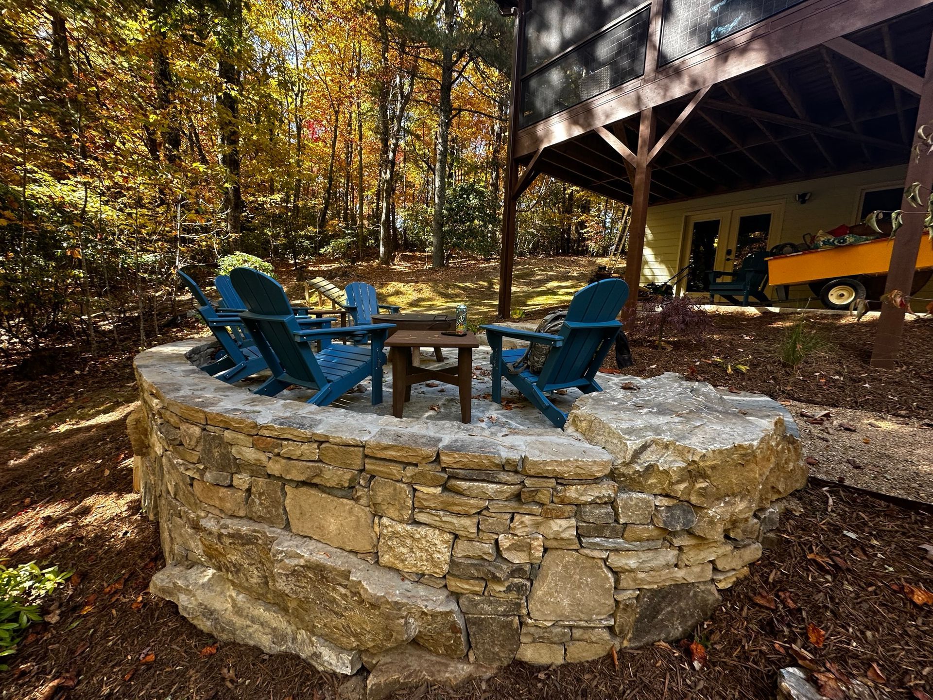 A group of blue chairs are sitting in a stone circle in front of a house.