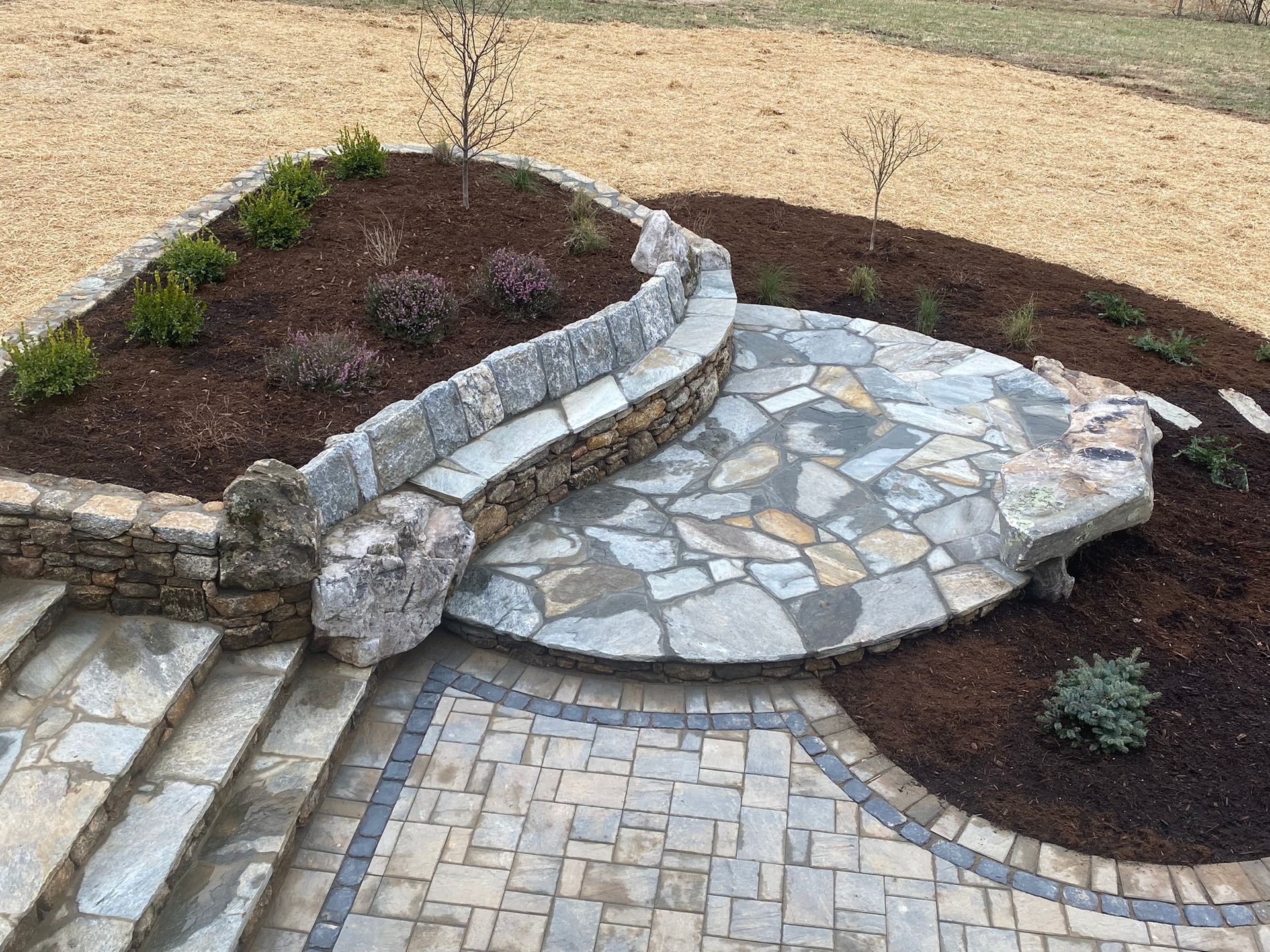 A stone patio with stairs and a stone wall surrounding it.