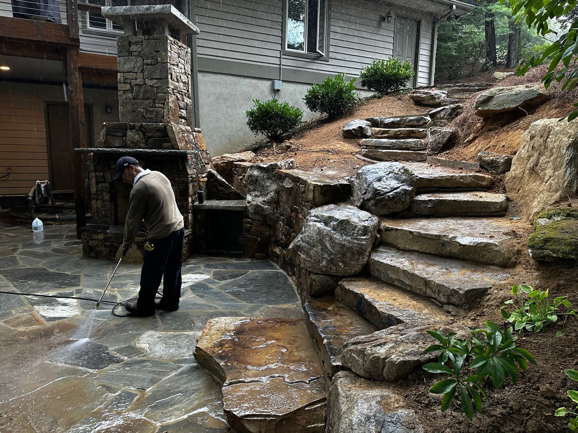 A man is cleaning a stone patio with a pressure washer.