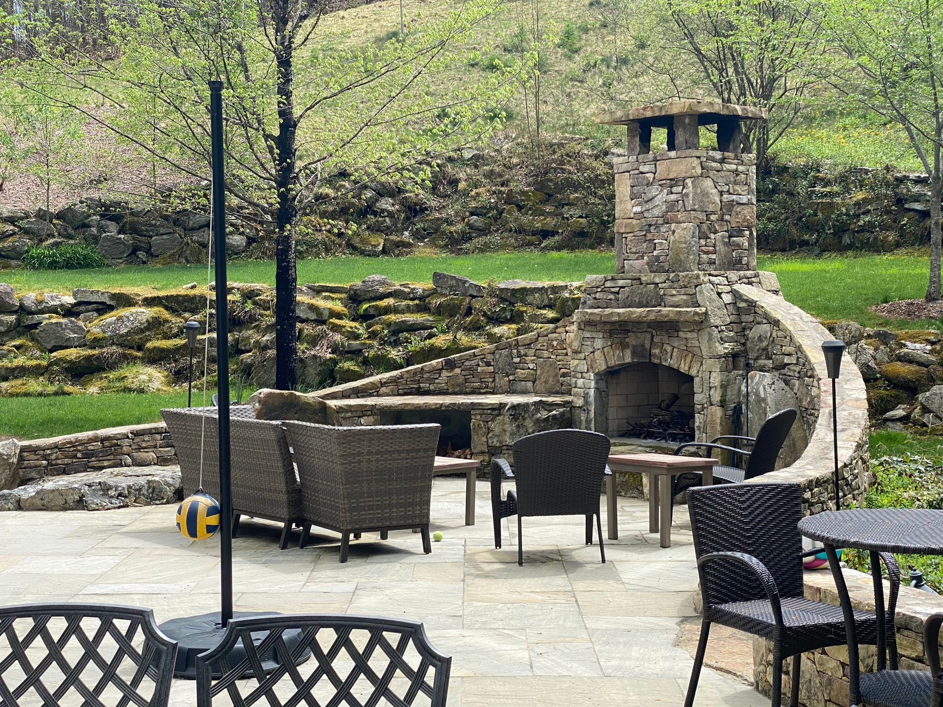 A patio with chairs, tables, and a fireplace.